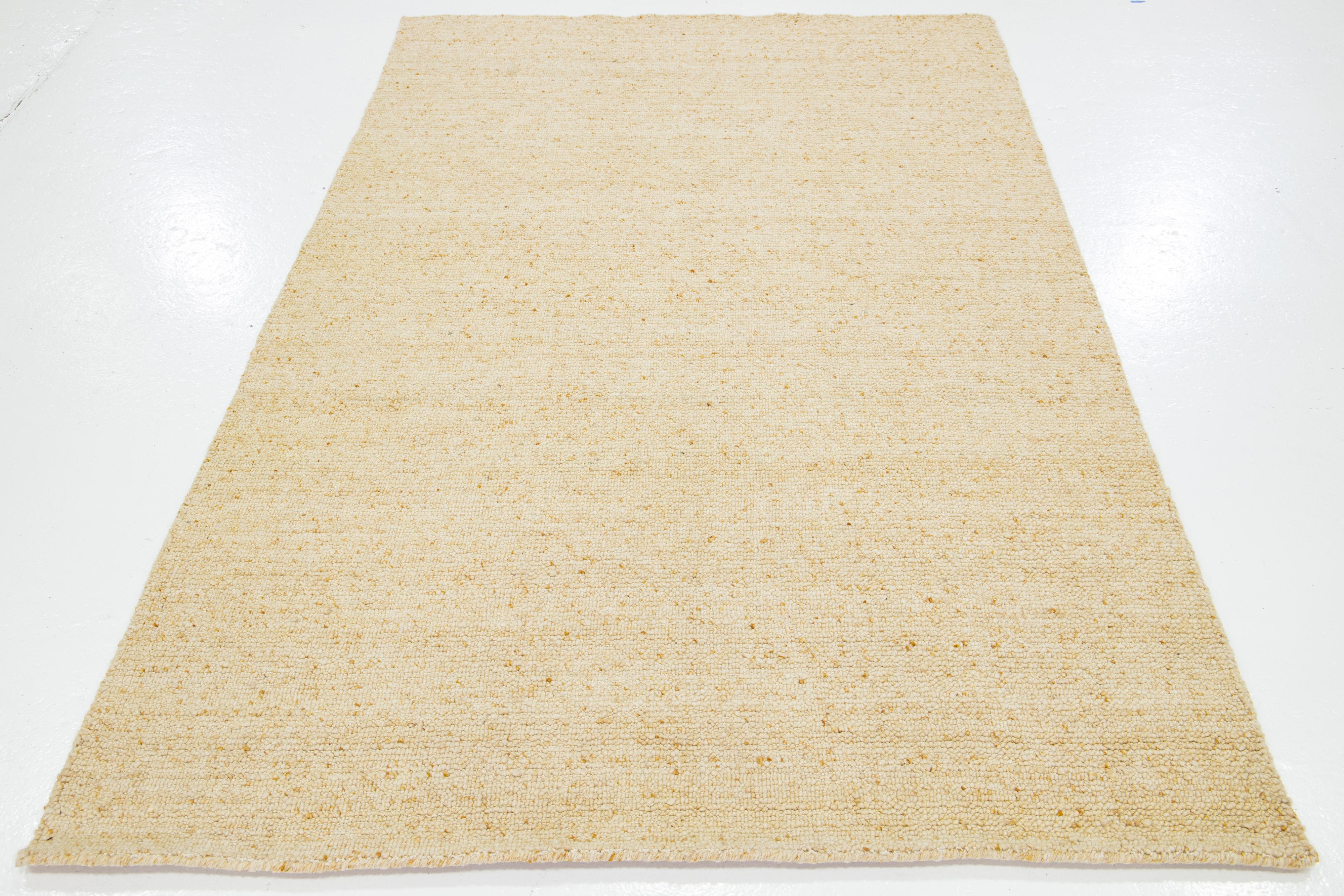 Dieser wunderschöne, modern strukturierte, handgeknüpfte Wollteppich aus der Collection'S Sasco zeichnet sich durch ein beigefarbenes Feld mit goldenen Akzenten und ein atemberaubendes, strukturiertes Muster aus, das an Kieselsteine