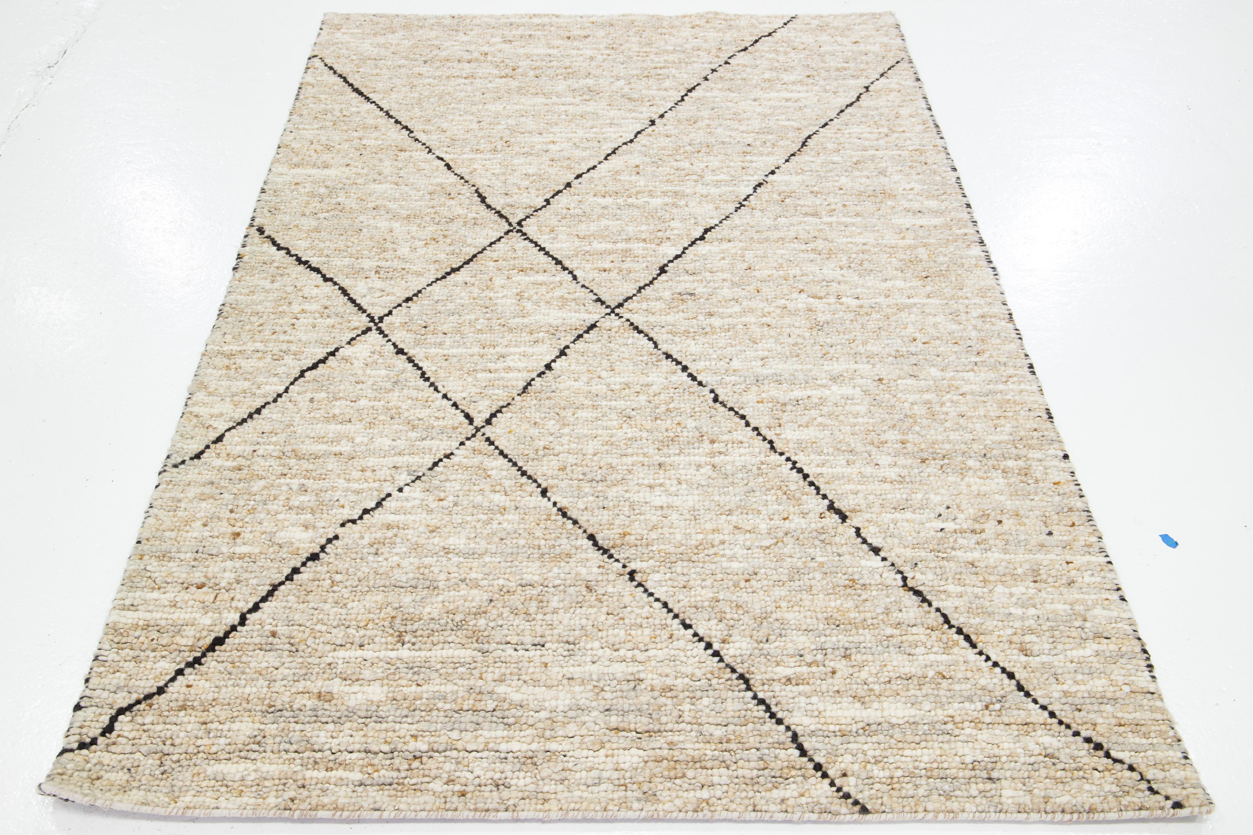 Dieser schöne, modern strukturierte, handgeknüpfte Wollteppich aus der Collection'Sasco zeichnet sich durch ein Farbfeld aus Beige und Braun aus. Der Teppich verfügt außerdem über ein atemberaubendes, strukturiertes Muster, das an Kieselsteine