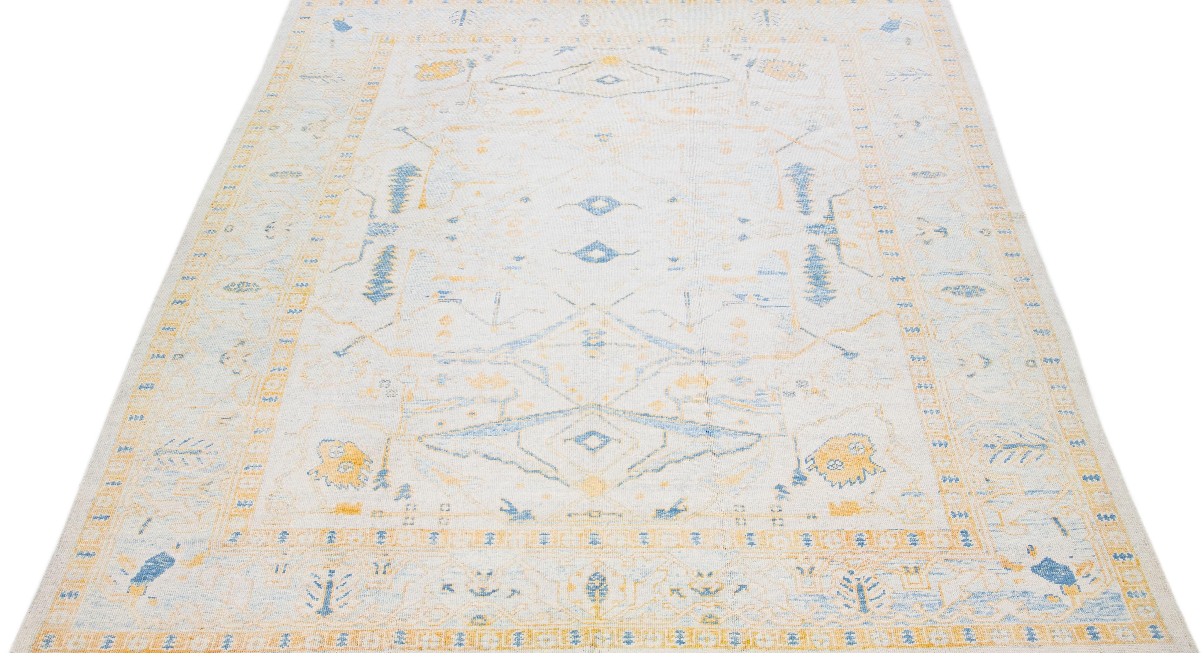 Beautiful modern Oushak hand-knotted wool rug with a beige color field. This Turkish Piece has blue and orange accent colors in a gorgeous all-over floral design.

This rug measures: 10'2