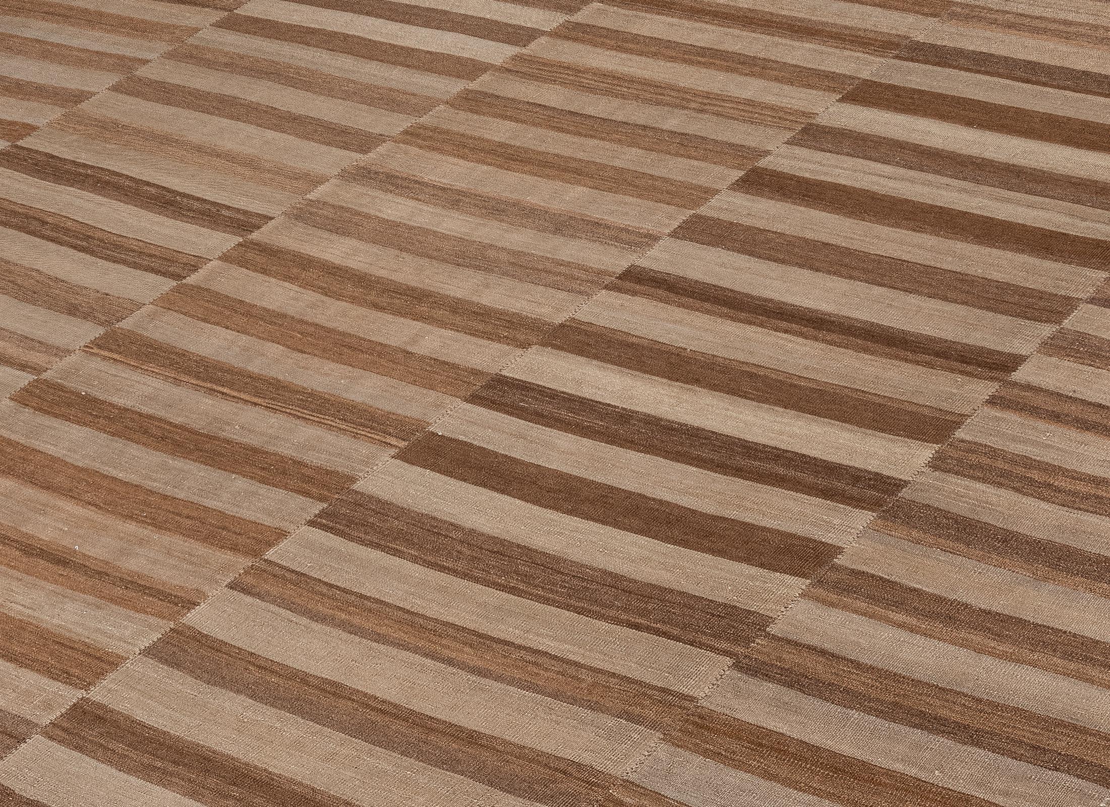 Questo moderno kilim tessuto a mano proveniente dall'Iran è realizzato al 100% in lana naturale non tinta e mette in mostra l'abilità e la precisione della tessitura tradizionale persiana. Il suo motivo a righe in tonalità neutre e morbide riflette