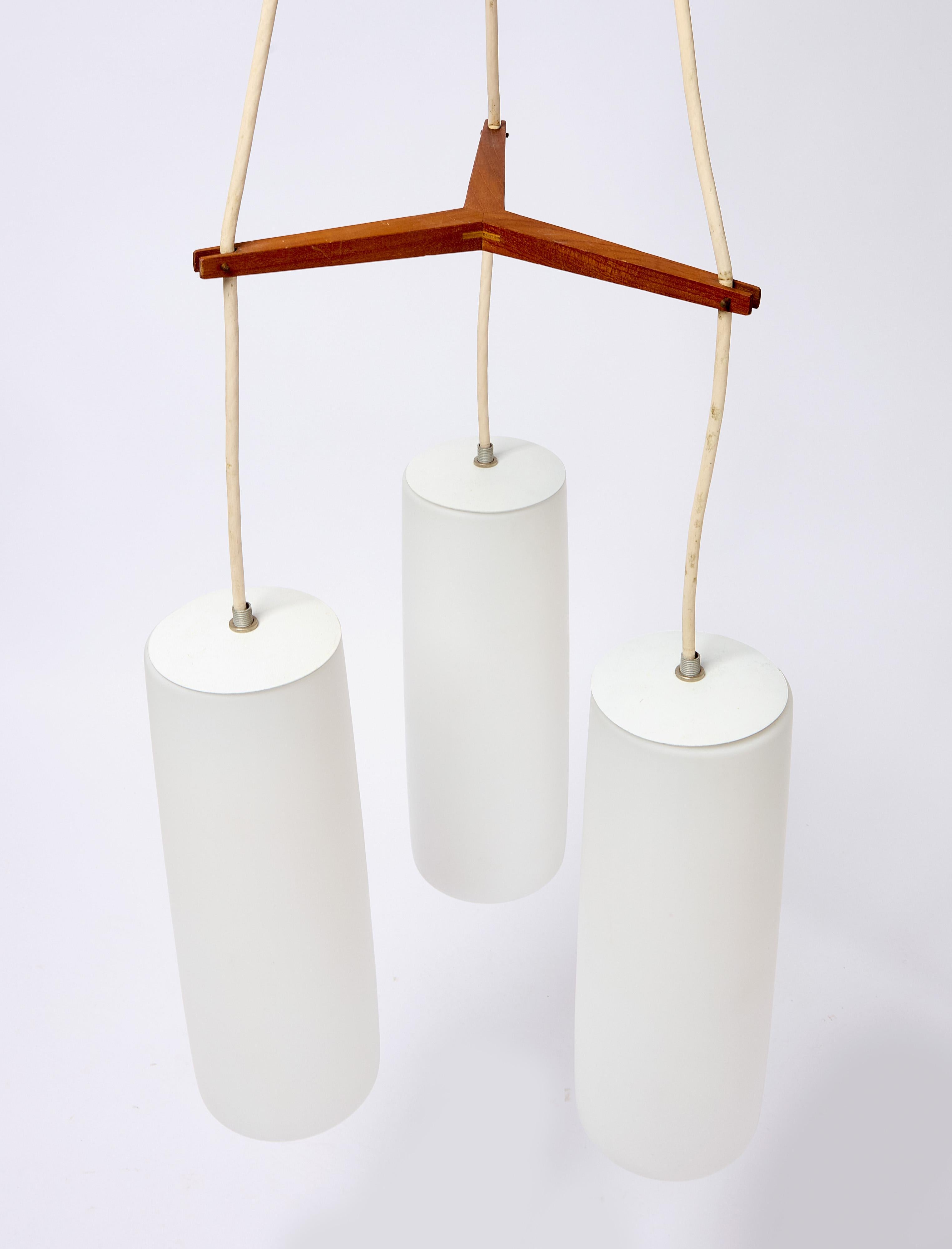 Lampada a sospensione moderna di Presco-Lite, Berkley California, circa 1965. Tre paralumi cilindrici in vetro sospesi con bracci in teak o noce. 
Ogni apparecchio include un paralume extra.

H. H. 27