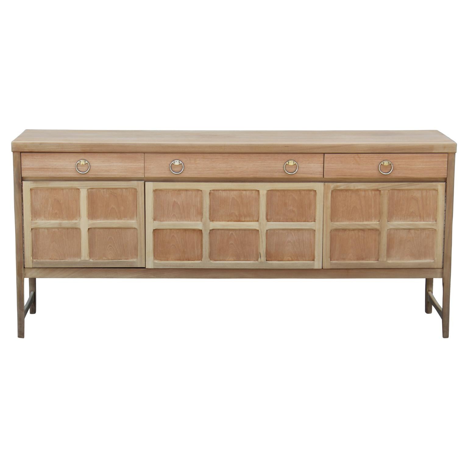 Freshly bleached sophisticated sideboard with brass ring handles. Centre cabinet drops down. Three drawers provide additional storage.