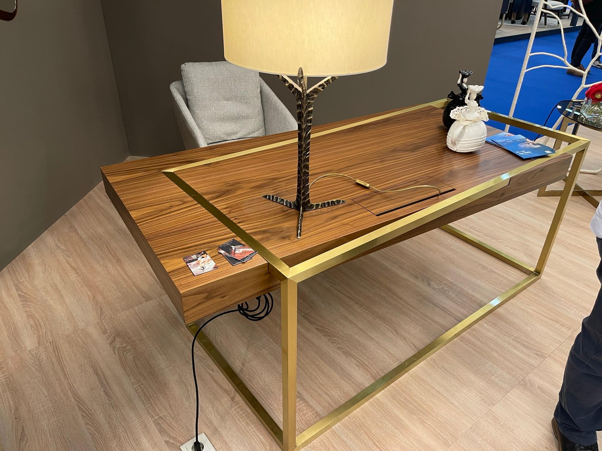 Le bureau de direction ExCentric 2.0, présenté ici, est fabriqué en bois de noyer et en laiton brossé. Il comporte deux tiroirs, des prises électriques et un chargeur de téléphone sans fil.
La pièce est en excellent état et a été utilisée comme