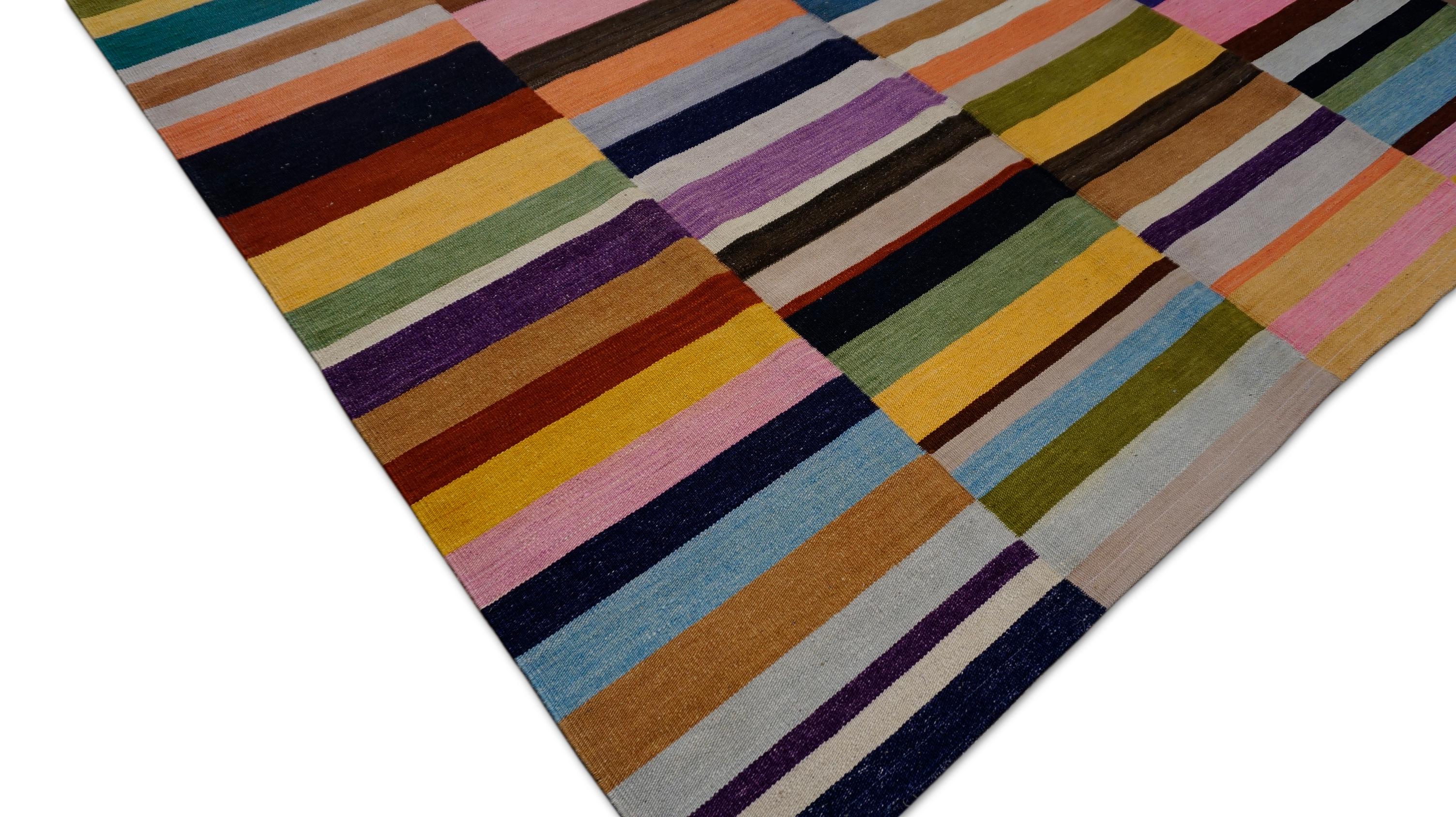 Dieser Kelimteppich aus Wolle ist eine kühne, moderne Interpretation traditioneller Handwerkskunst, die mit ihrer lebhaften Farbpalette und strukturierten Geometrie jeden Raum belebt. Der Teppich zeichnet sich durch eine auffällige Komposition