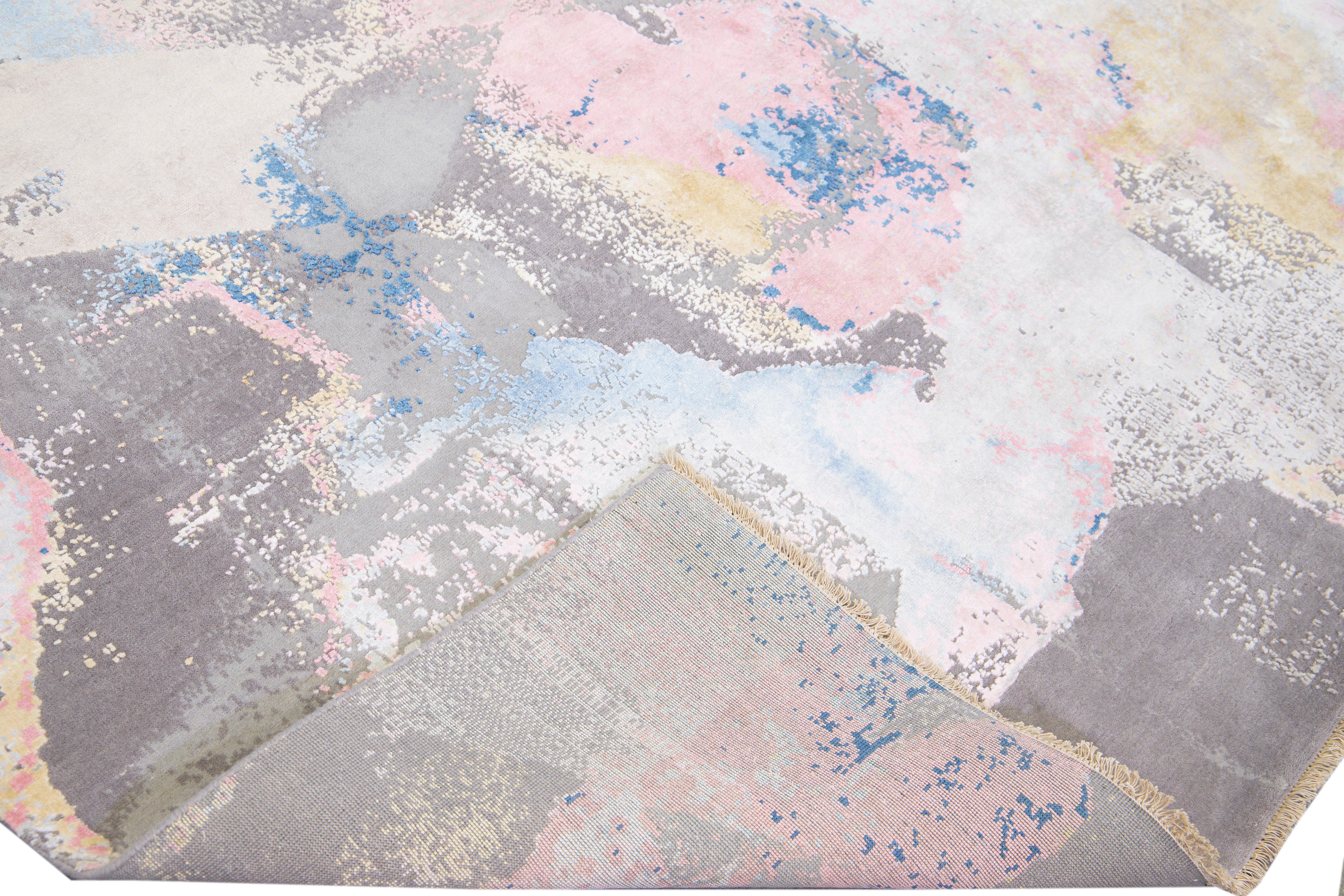 Bellissimo tappeto indiano moderno annodato a mano in lana e seta con campo grigio. Questo tappeto moderno è caratterizzato da accenti beige, blu, rosa e gialli e da uno splendido disegno astratto espressionista.

Questo tappeto misura: 9'1