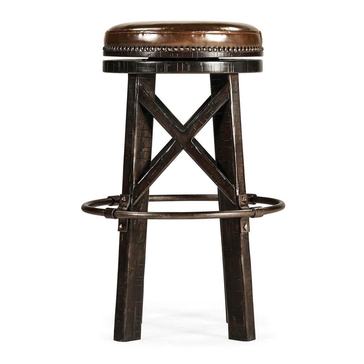 An industrial modern solid dark ale finish round bar stool, the planked legs with exposed saw marks to the rustic finish, beneath a studded leather twist seat and an iron circular footrest.
 

Dimensions: 20