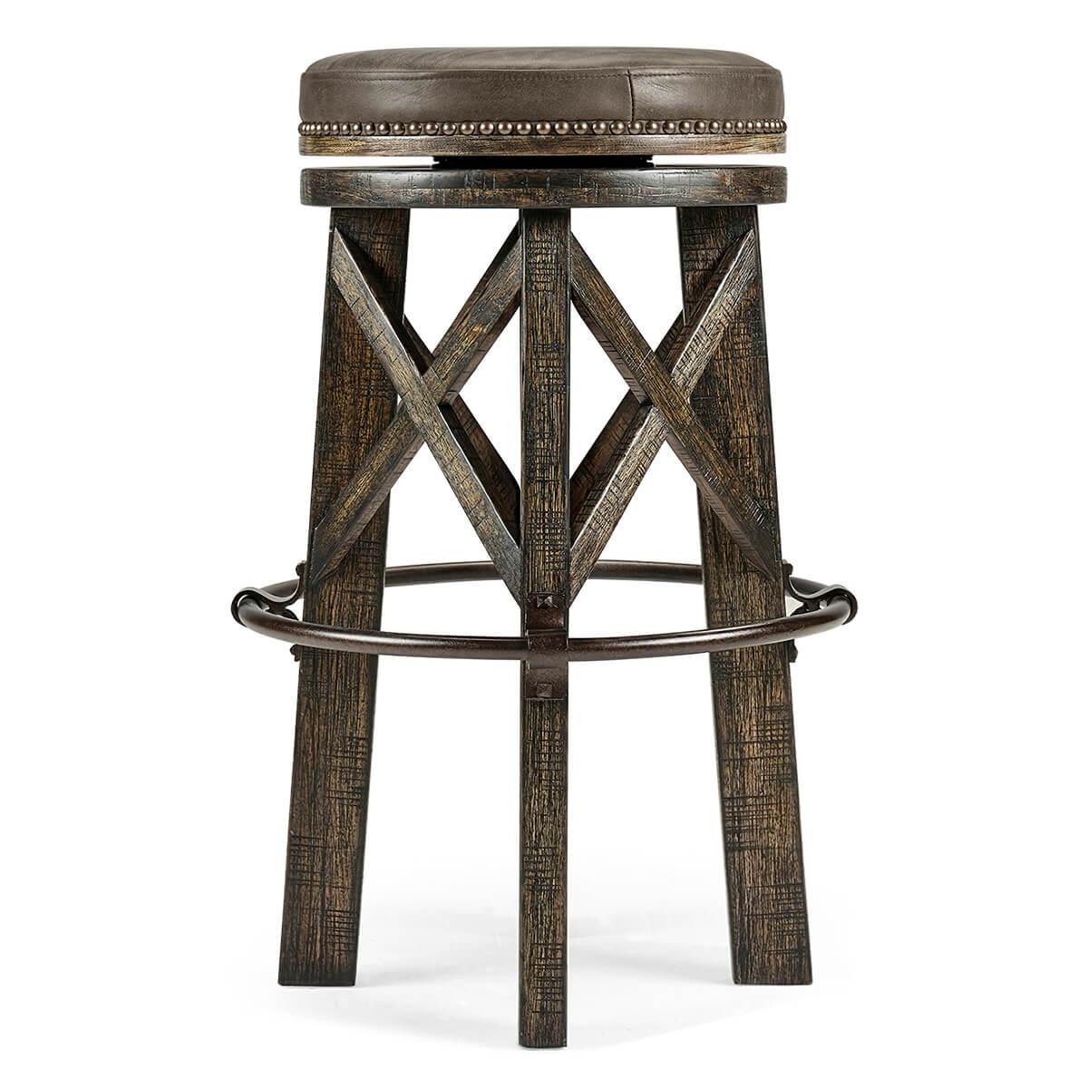 An Industrial modern solid dark driftwood round bar stool, the planked legs with exposed saw marks to the rustic finish, beneath a studded leather twist seat and an iron circular footrest.
 

Dimensions: 20