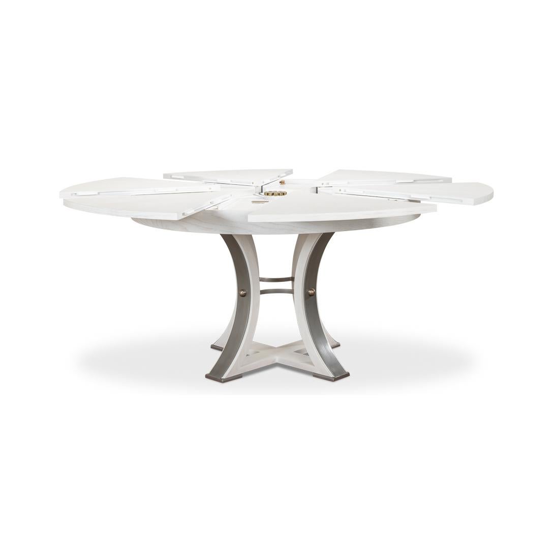 Une table de salle à manger extensible ronde de style industriel moderne. Plateau en chêne brossé dans notre finition blanche de travail avec des accents de fer à canon sur la base de forme géométrique simple. La table s'ouvre et s'allonge jusqu'à