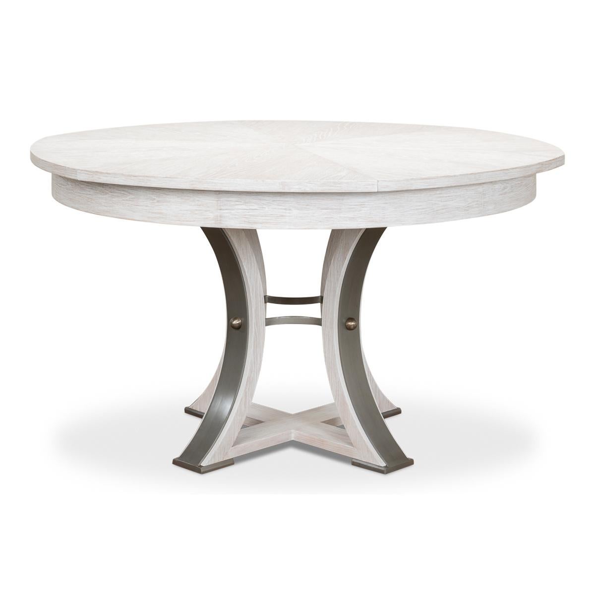 A modern industrial style round extending dining room table. Wire brushed oak top in our working white finish with gunmetal iron accents to the simple geometric form base. The table opens and extends to 70