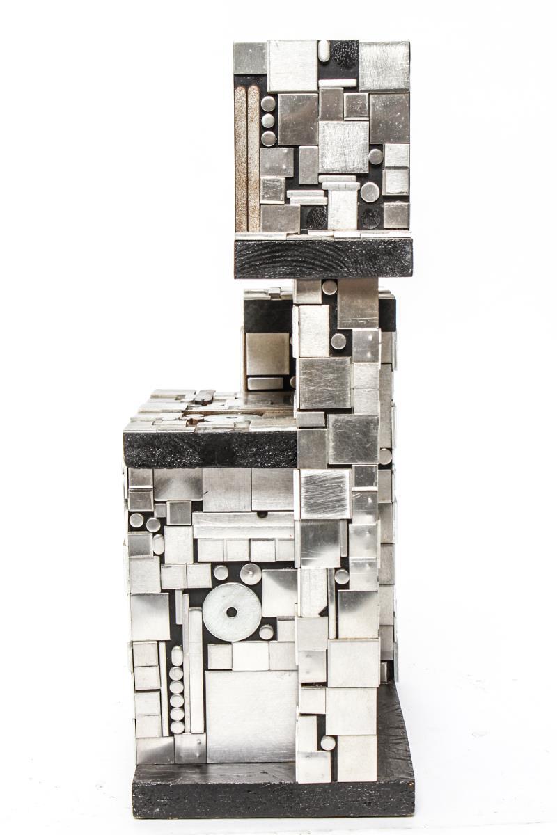 Modern Industrial style tabletop sculpture titled 'Surface tension' and made of small black-painted wood parts staggered in linear shapes and covered in aluminum dots, squares and bars. The piece is mounted on a black-painted wood base and is