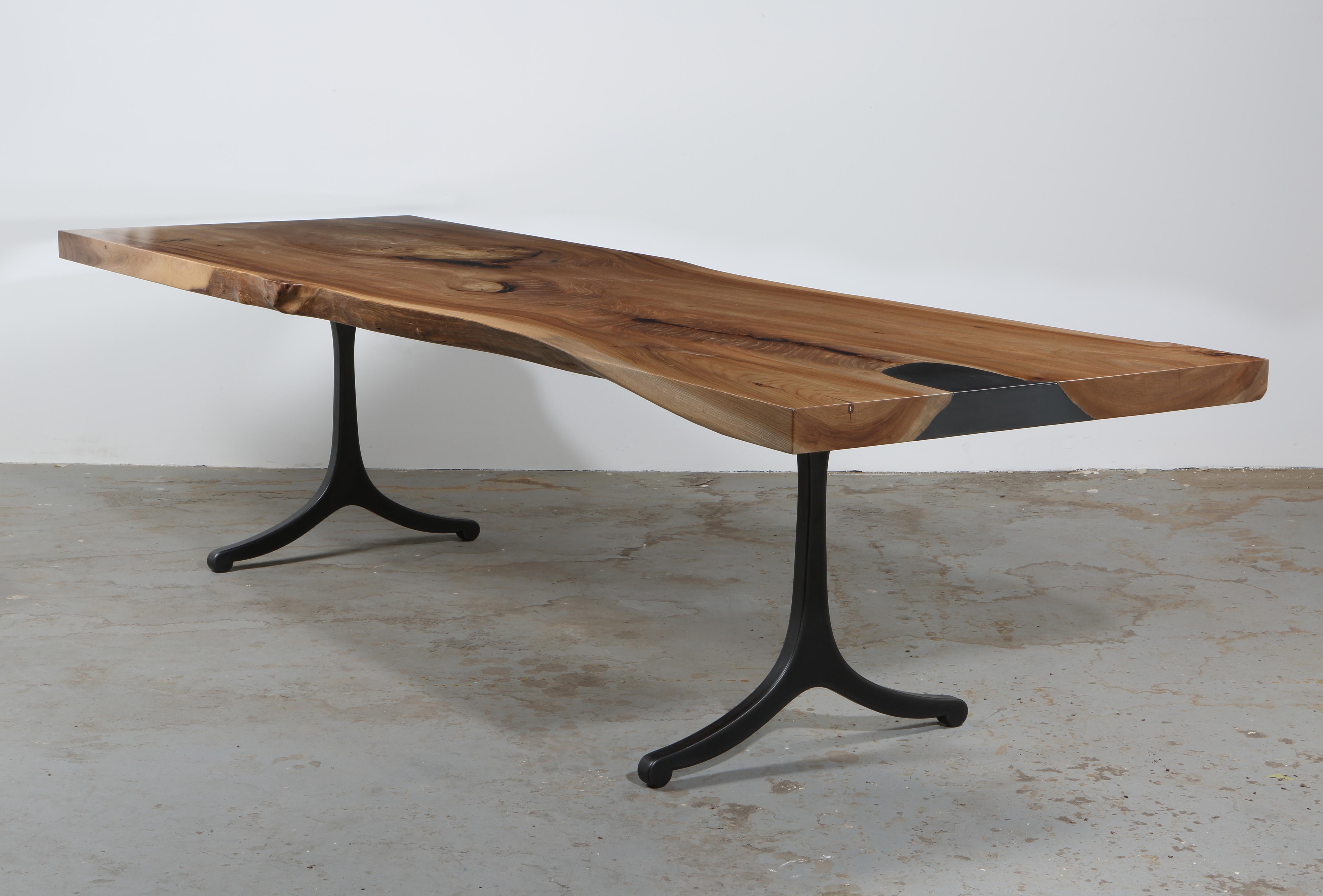 Serif Series dining table

A single slab of 3” thick elm, with just a hint of live edge left intact. Grain matched steel inlay with removable plate revealing hidden storage. Signature Serif Leg in flame cut/blackened finish. Please note that each
