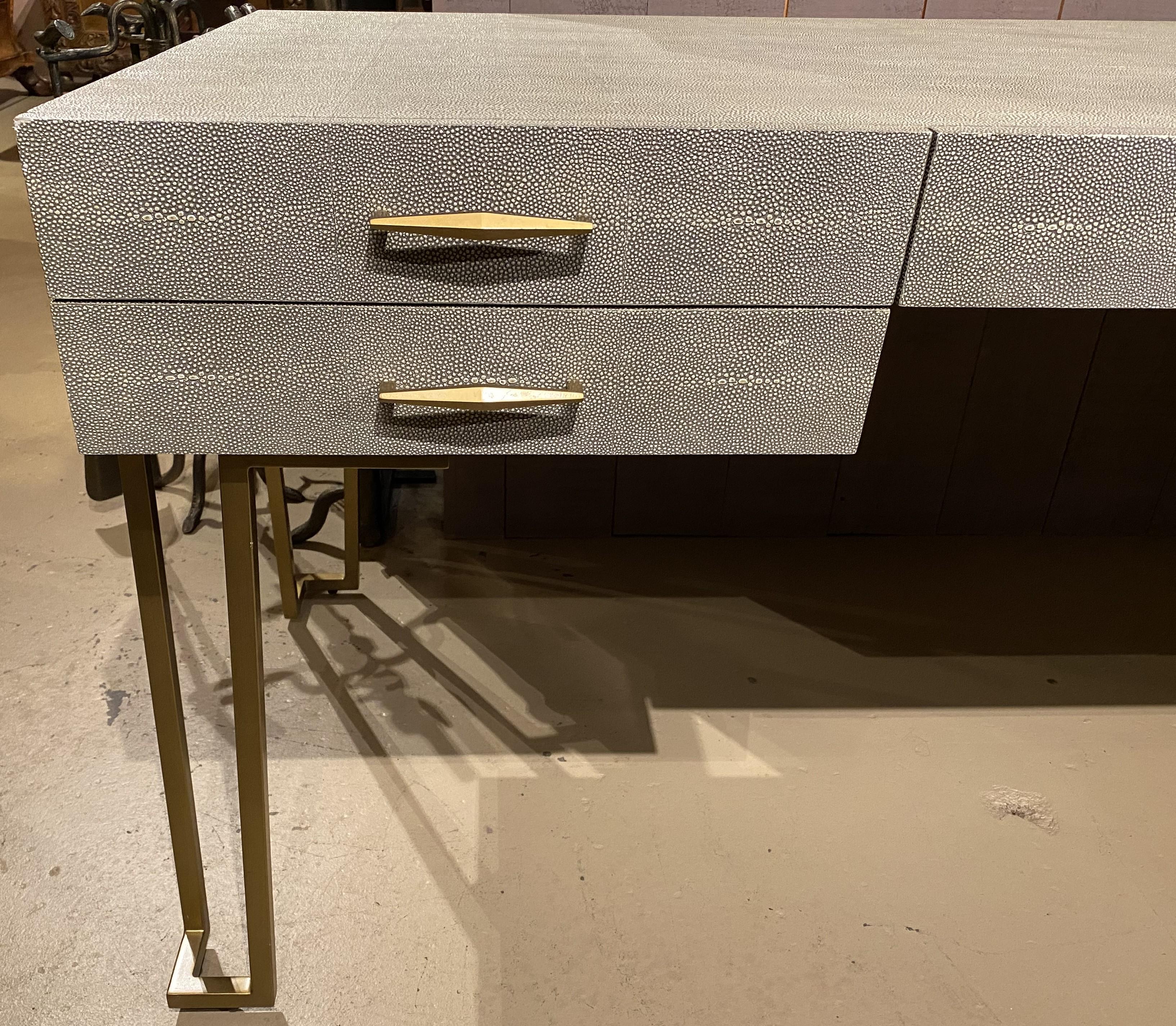 A sleek five drawer modern Morand grand desk in faux shagreen and sorrel gray by Interlude from the Interlude Home Collection, based in Trumbull, Connecticut, with brushed brass legs and hardware, and a manufacturer’s brass tag inside top left