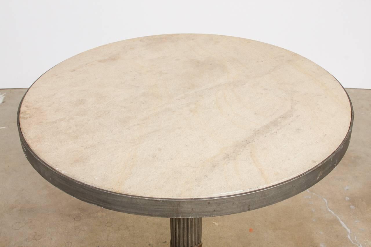 Bespoke modern iron and travertine limestone centre table or pub table made in a counter height size. 2 inch thick round disk of honed natural stone perfectly fit into an iron frame. Features a neoclassical style column support with a decorative
