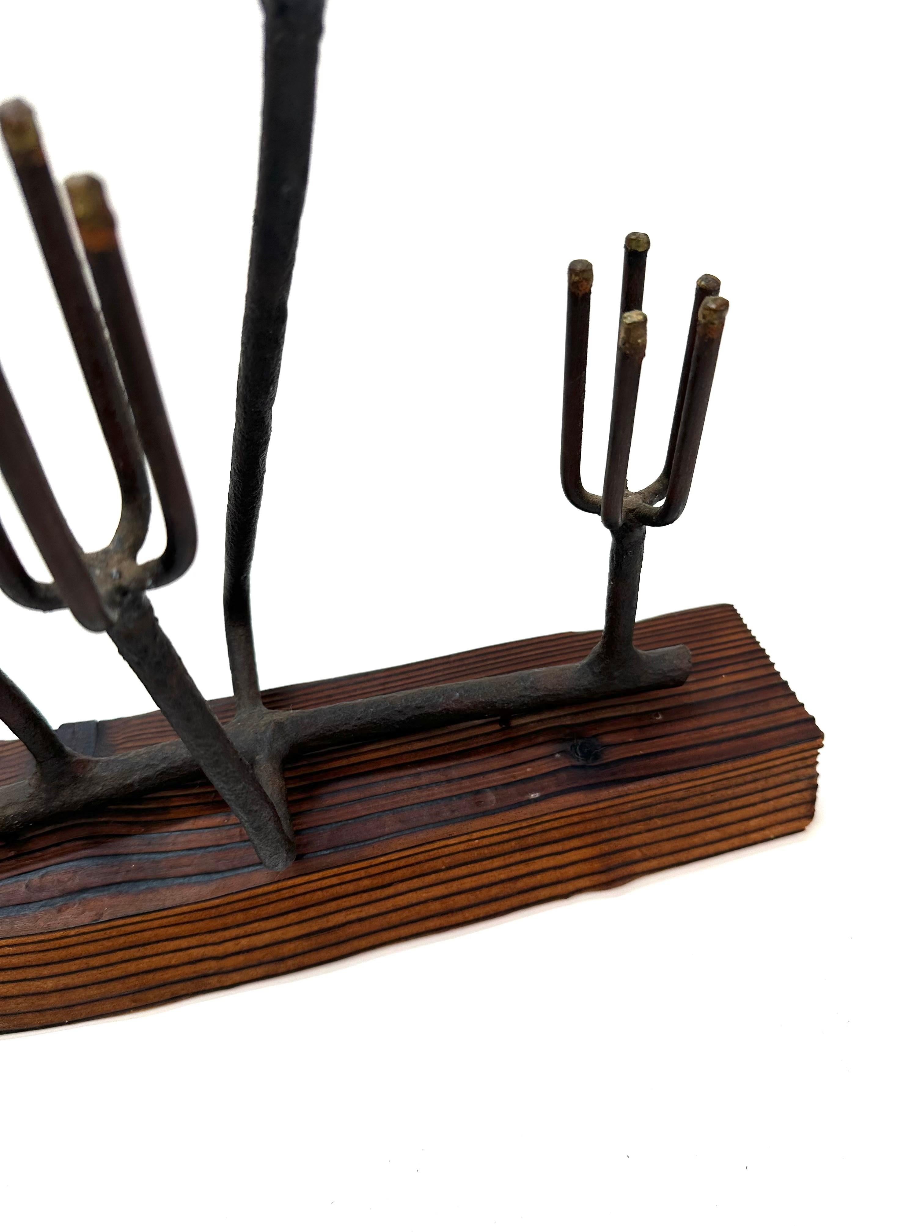 Diese abstrakte Eisenskulptur ist ein eindrucksvolles Beispiel für das moderne Design der kalifornischen Mitte des Jahrhunderts. Sie besteht aus einer Reihe aufrechter, gegabelter Stäbe, die sich organisch von einem reich gemaserten, geschnitzten