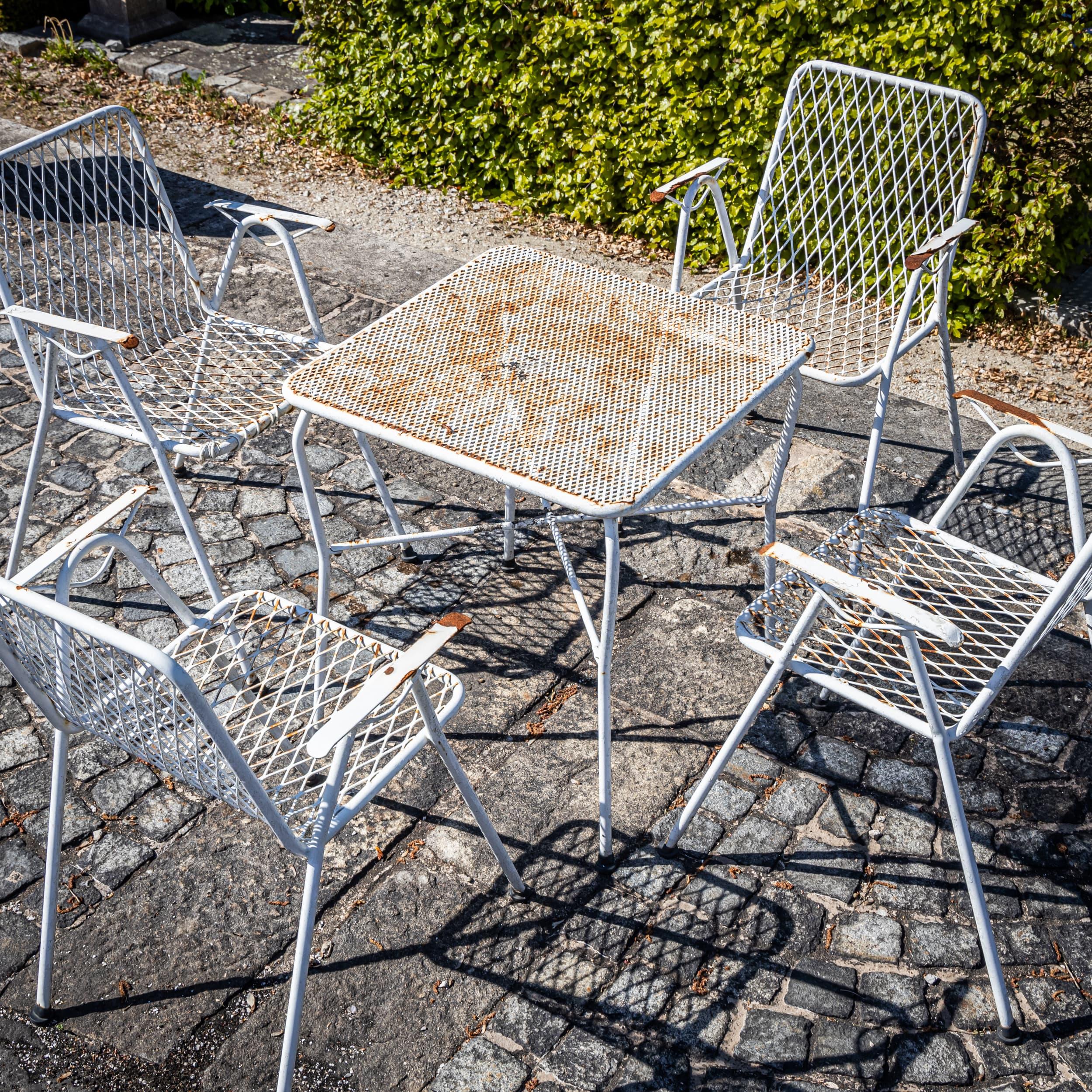 Elegante set di sedute in metallo verniciato di bianco, probabilmente realizzato in Italia intorno alla metà del XX secolo. Composto da quattro sedie e un tavolo quadrato coordinato, il set presenta linee pulite e una struttura a traliccio