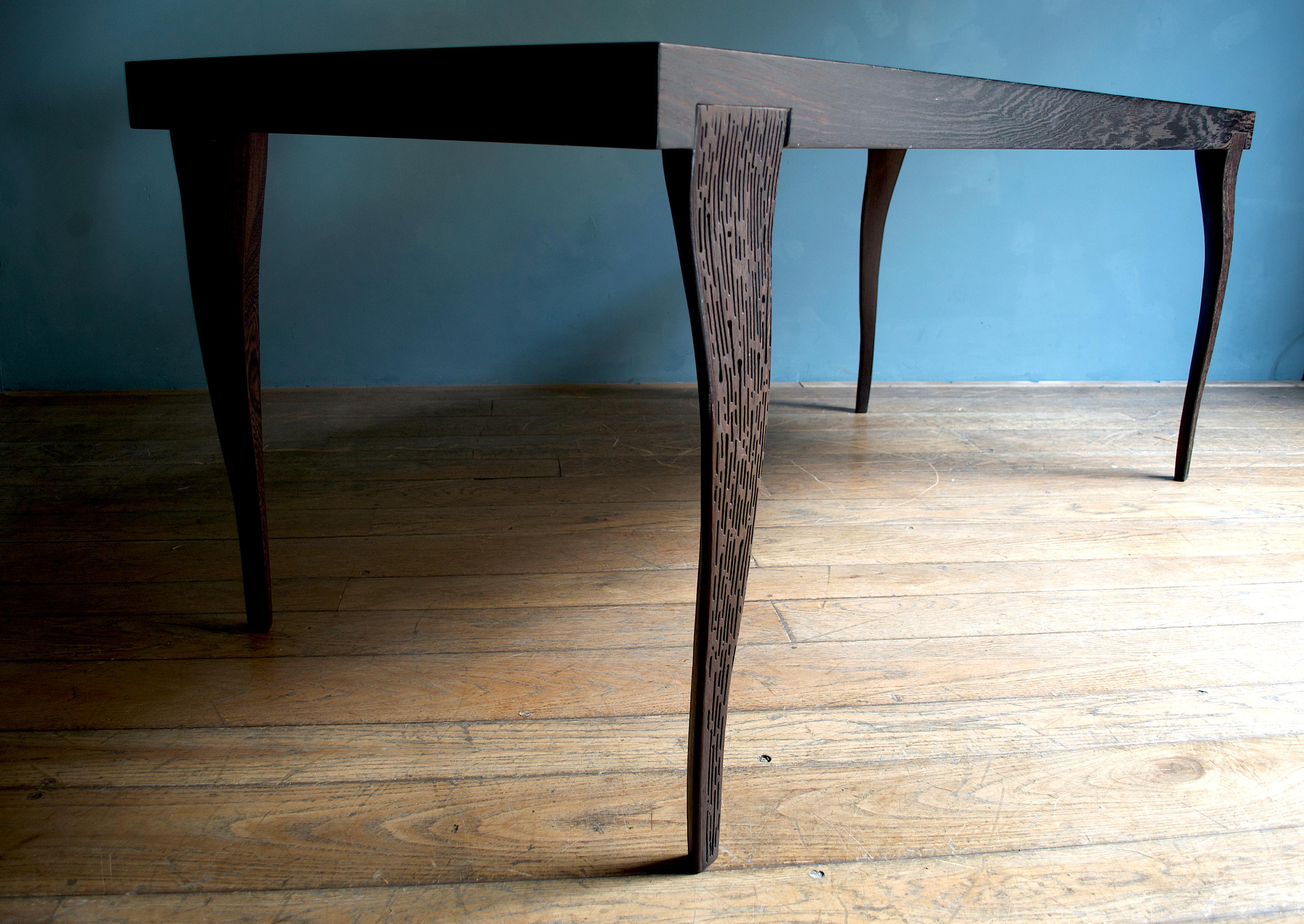 This minimalist table in wenge wood displays high craftsmanship in all its details, from the top covered by a masterfully-applied sheet of oxidized and polished brass to the four solid carved wood legs. All the solid wood parts as the edge, are