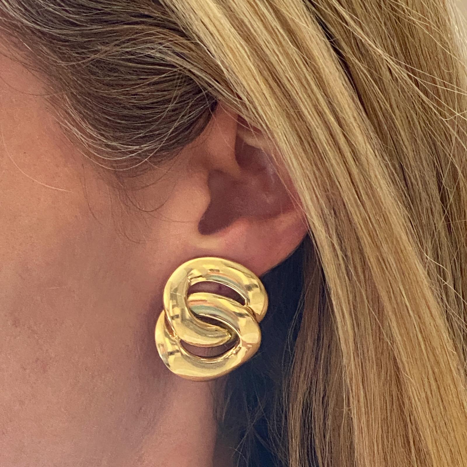 Italian interlocking circle earrings are fashioned in high polish 18 karat yellow gold. The earrings currently have clip lever backs (posts can be added), and measure 1.0 x 1.25 inches. 