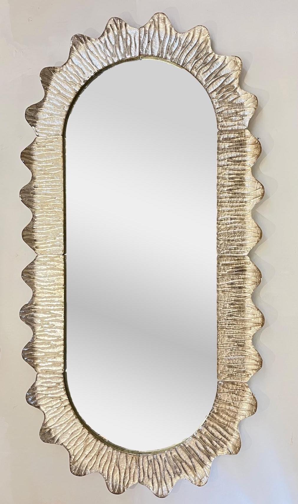 This handcrafted Venetian mirror with a ruffled organic curved frame in blown Murano glass, made in Italy, is worked with crystal glass in a champagne tint that is decorated on reverse with pure silver leaf that creates an elegant and luminous