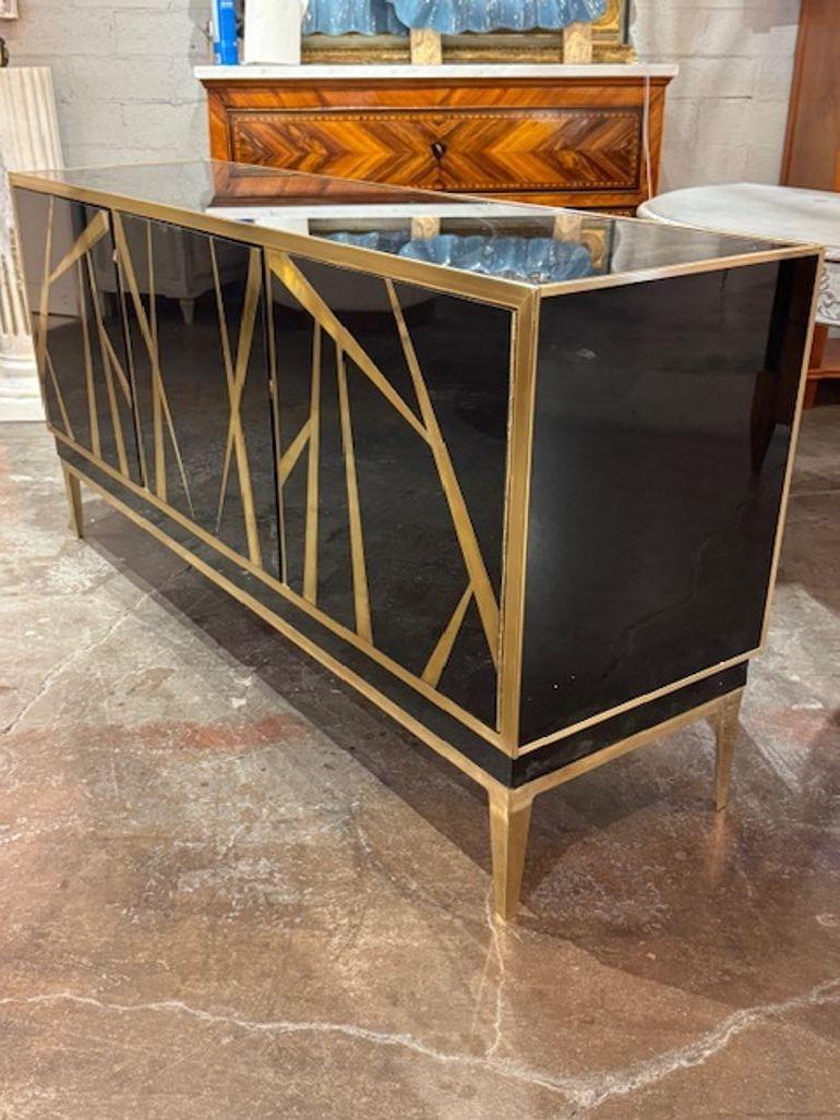 La credenza moderna italiana laccata nera e in ottone emana raffinatezza ed eleganza. L'elegante finitura laccata nera abbinata ai dettagli in ottone aggiunge un tocco di lusso a qualsiasi ambiente. Questo elegante mobile è perfetto per chi desidera