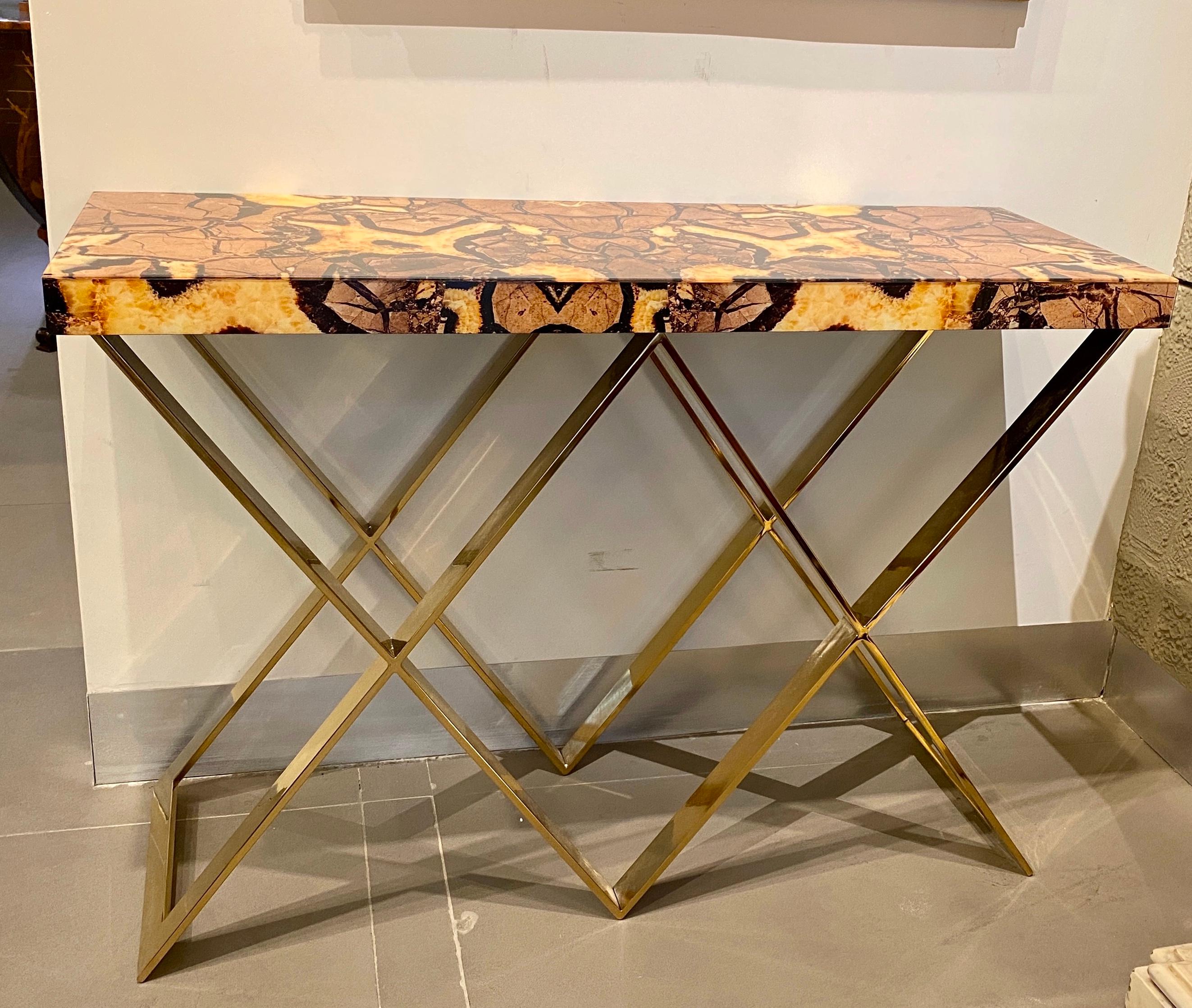 Exceptional console Table with double X-shaped brass base .
The glass tops of these pair of consoles are made with the imitation of a semi-precious stone called “septaria”, which is formed by overlapping mineral deposits and is crossed by crystal