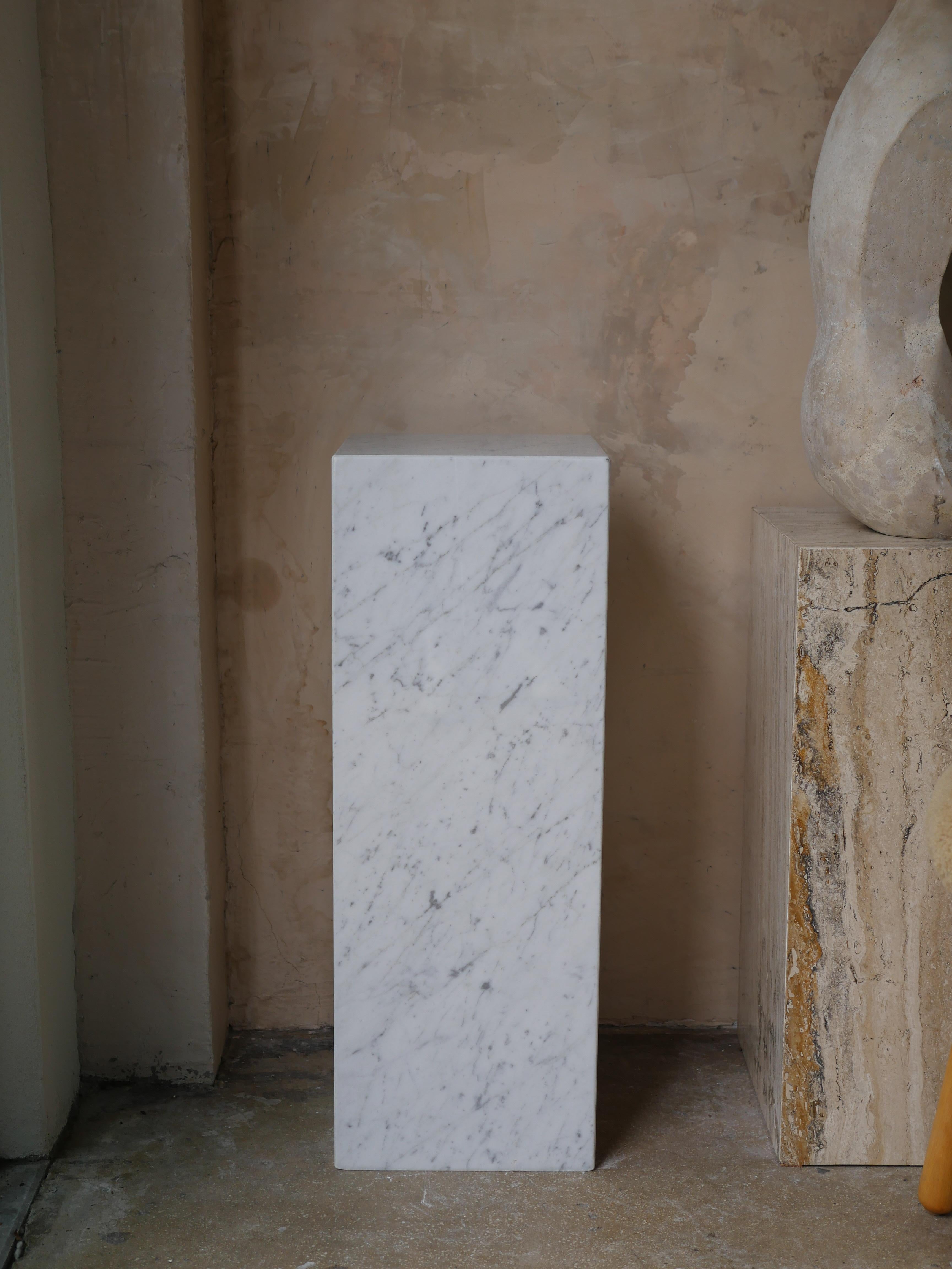 Elegant modern, custom made Italian Carrara marble pedestal. This beautiful pedestal is perfect for adding a varying height to your space, while providing a stunning addition for showcasing your sculptures with style.