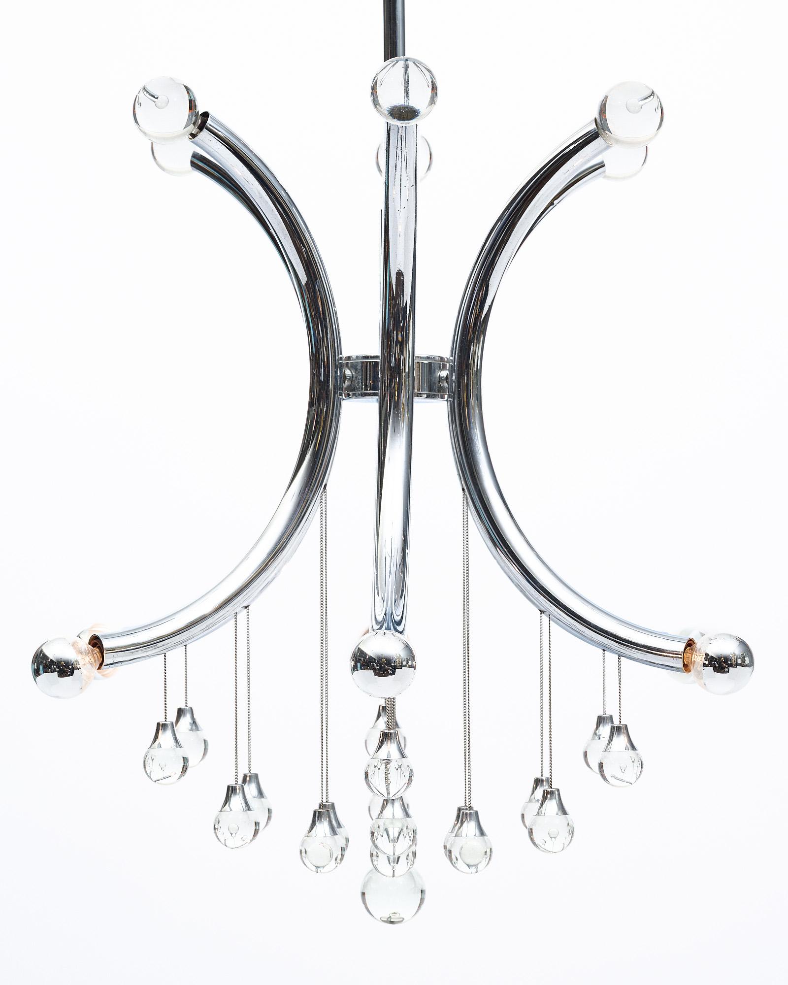 Vintage chandelier from Italy featuring a chrome structure of semicircle arms emanating out from the center. Each arm has a crystal finial at the top and a light at the bottom. The structure has crystal drops falling from the body as well, giving it