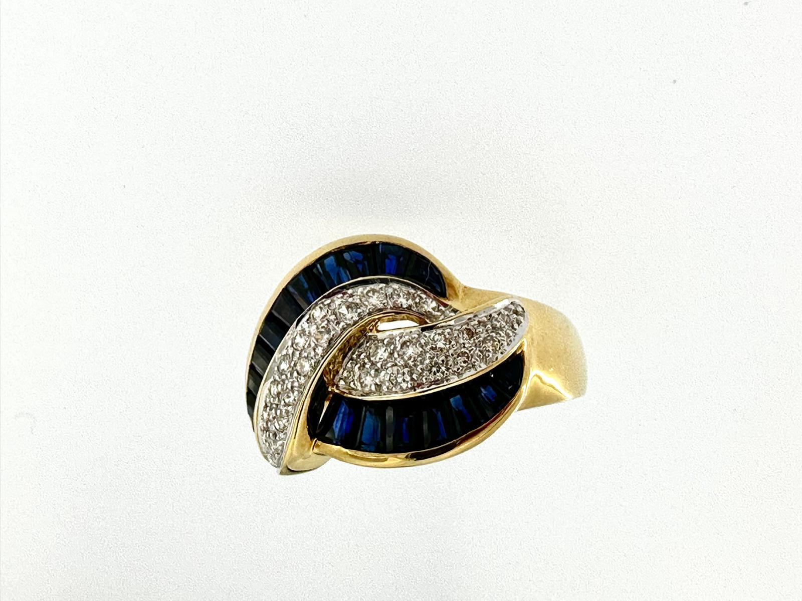 El moderno anillo de cóctel italiano es una impresionante pieza de joyería elaborada en oro amarillo de 18 quilates. Presenta una lujosa combinación de diamantes talla brillante de 0,27 ct y zafiros talla baguette de 0,90 ct, que añaden un toque de