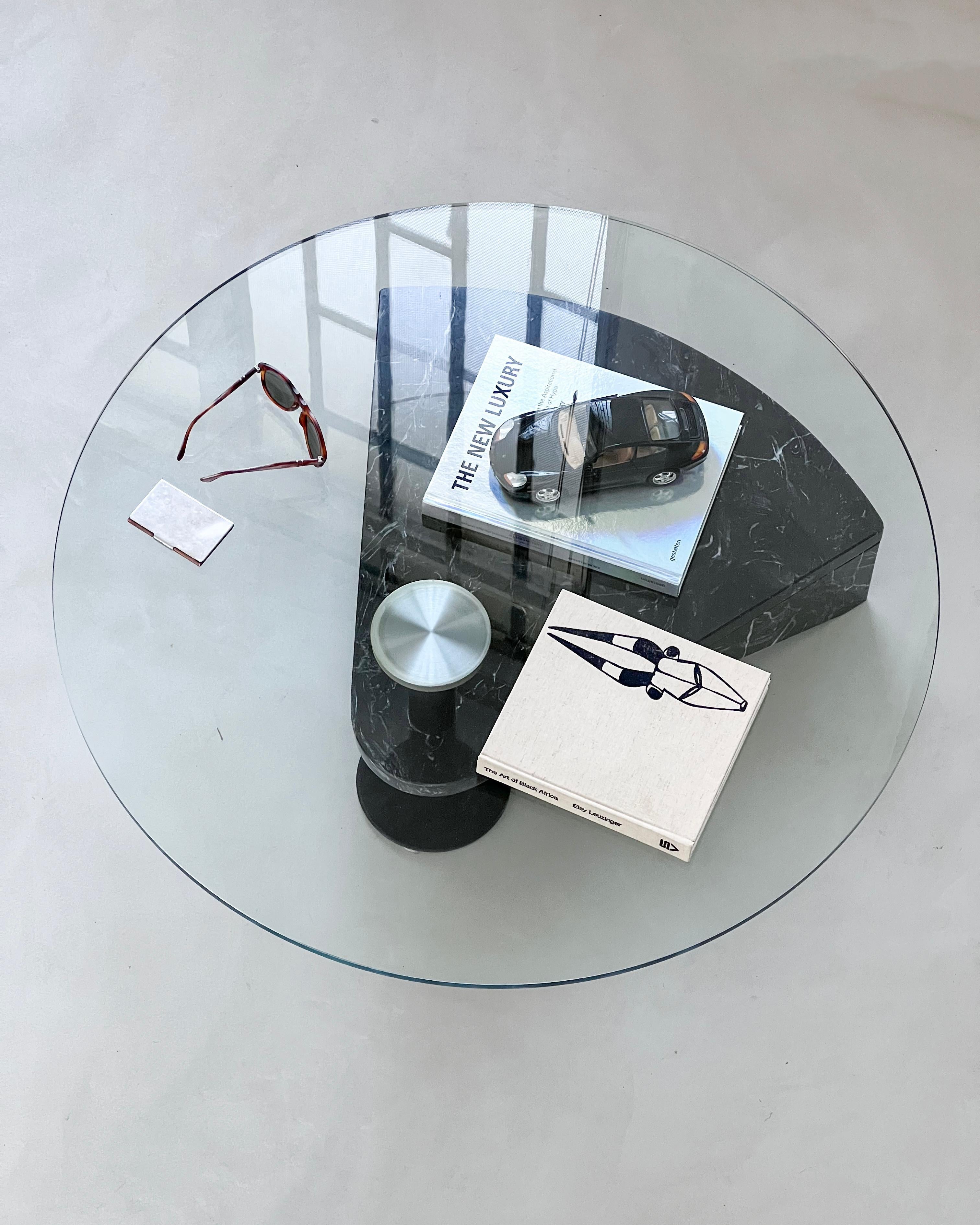 Sculptural modern coffee/cocktail table in black marble and glass by Acerbis, Italy, dating to the 1990s. It's a very nice, architectural piece, that looks great from every angle and is extremely satisfying to style. The black marble base also