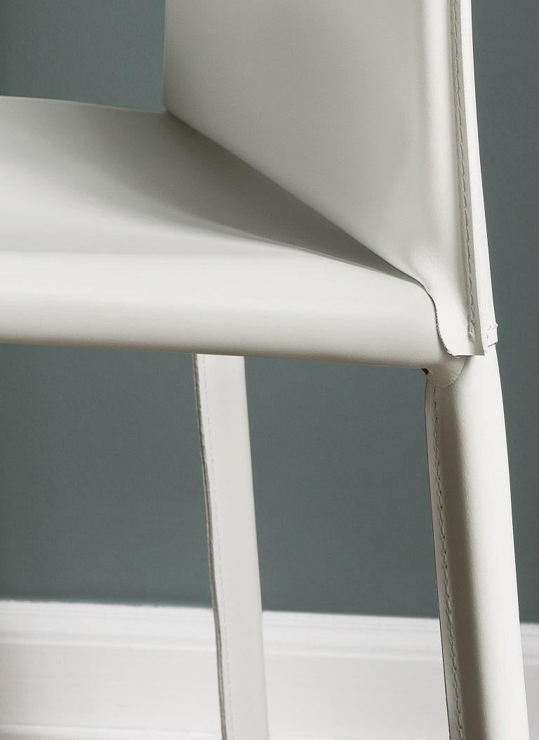 Conçue par Daniele Molteni, la chaise Linda fait partie d'une famille de chaises et de tabourets. Cette chaise Linda, à haut dossier, a une structure métallique entièrement rembourrée et recouverte de cuir blanc avec des coutures assorties. Il est