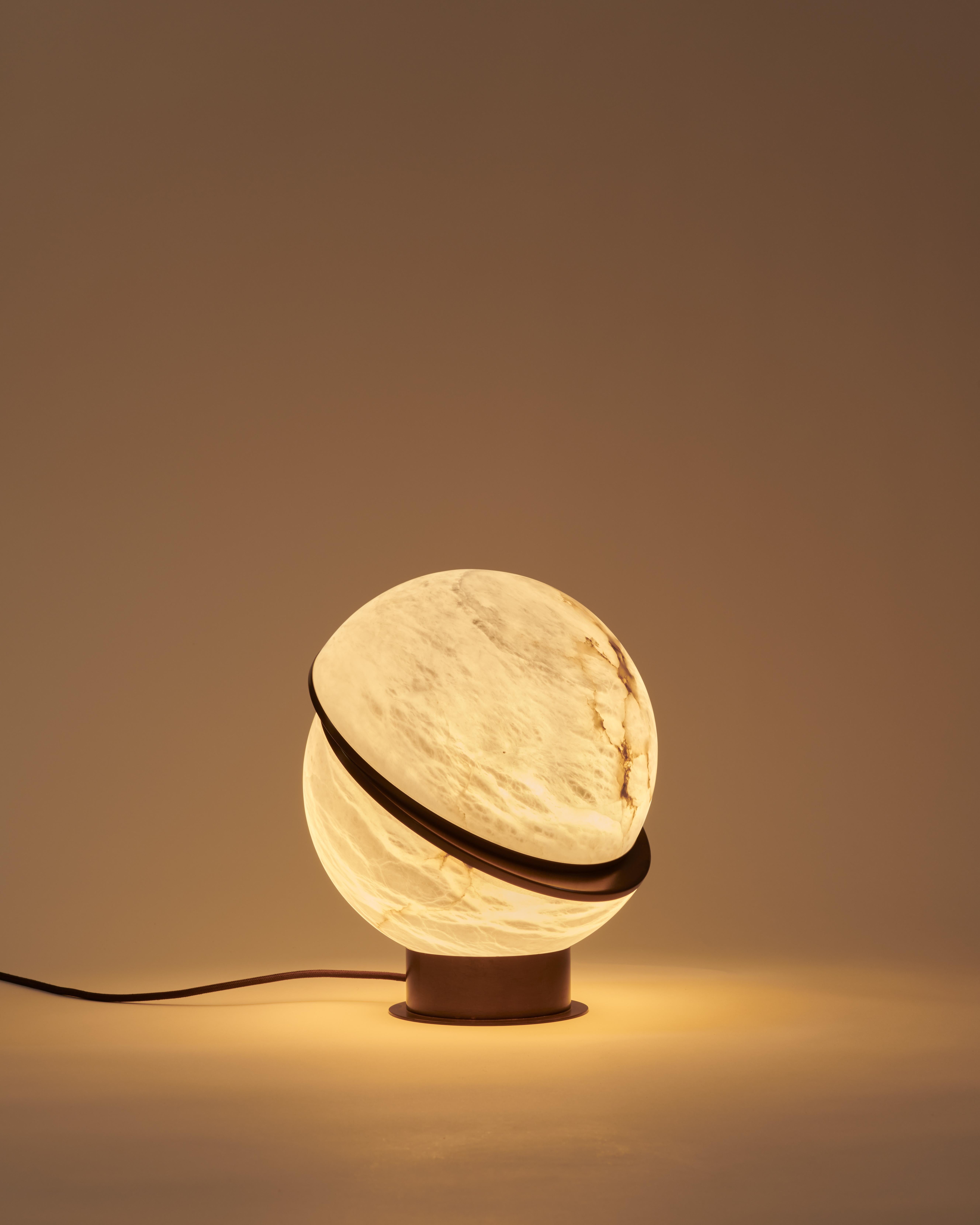 La lampe à poser Alabaster Globe est une pièce étonnante qui respire l'élégance et la sophistication. La lampe présente deux demi-sphères d'albâtre rétroéclairées, maintenues ensemble par un fin contour en laiton. La magie des veines de l'albâtre