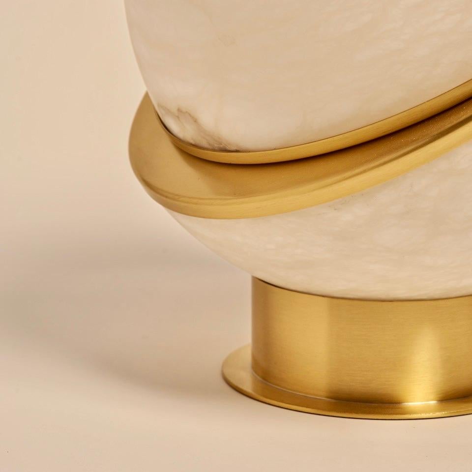 The Alabaster Globe table lamp is a stunning piece that exudes elegance and sophistication. The lamp features two half spheres of backlit alabaster, held together by a thin brass contour. The magic of the alabaster's veins is showcased through the