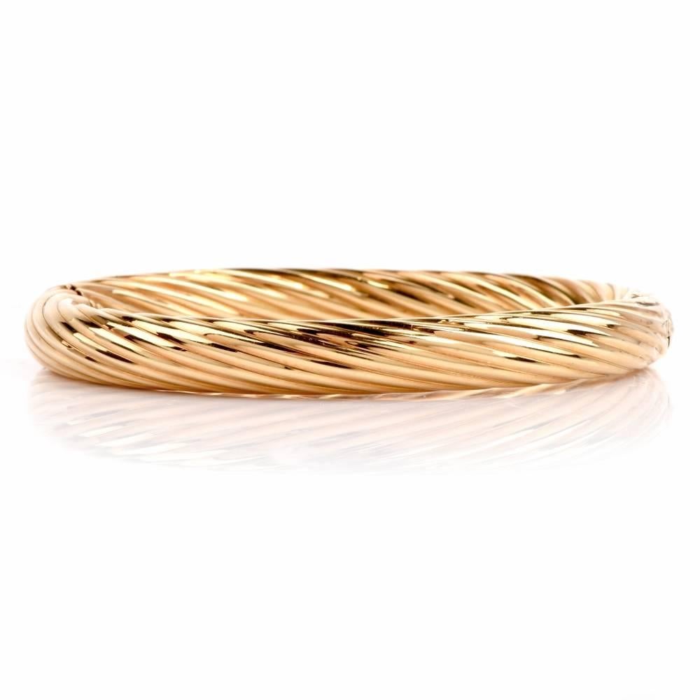 A classically elegant vintage bangle bracelet of Italian provenance, bearing the official Hallmark of Italy on its insert tongue-in-groove clasp. It is crafted in ornately textured 18 carat polished yellow gold, depicting artfully rendered ' en