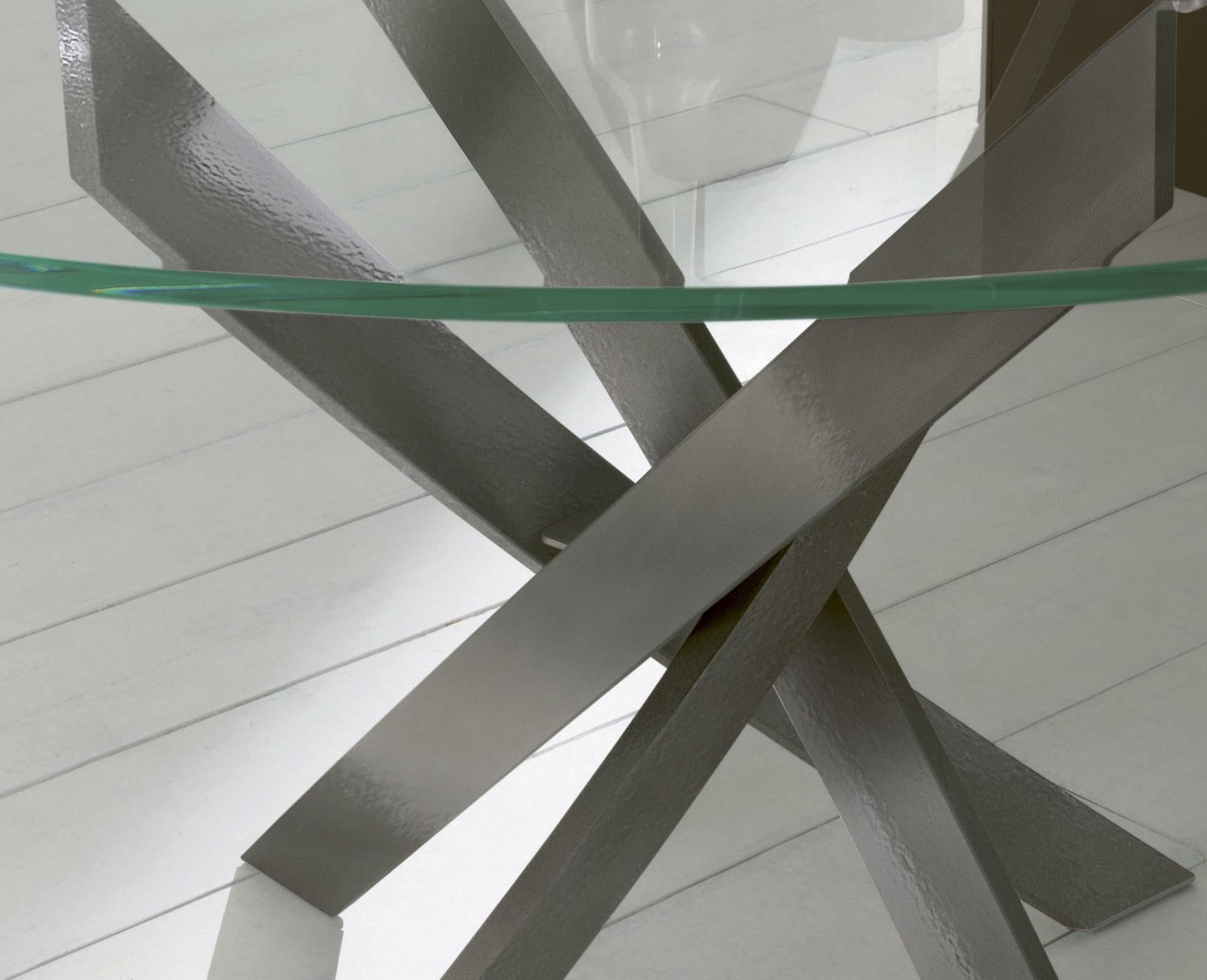 Dieser von Pocci&Dondoli entworfene Tisch zeichnet sich durch eine harmonische Drehung der geschwungenen Bögen aus, die seine einzigartige Basis umreißen. Das runde Oberteil besteht aus transparentem, extra klarem Glas, das auf einer extra leichten