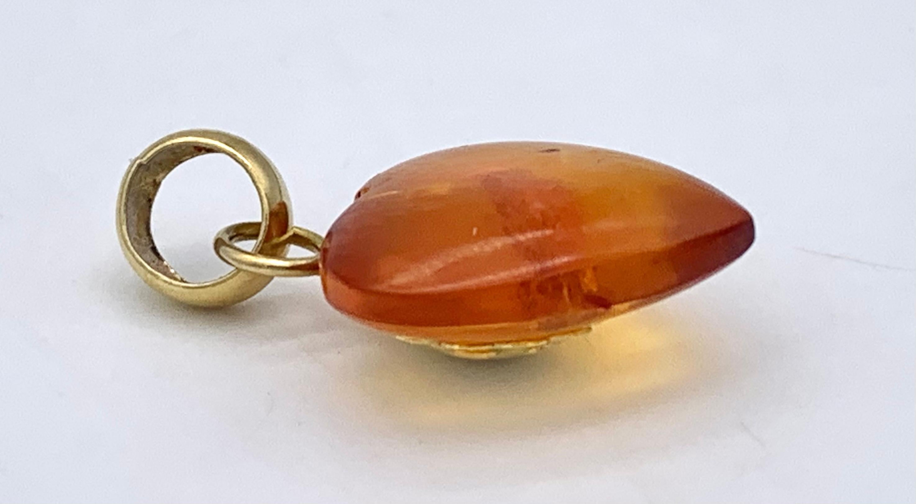 This charming modern amber heart pendant is marked 750 on the decorative large eyelet and is impressed with an Italian hallmark. The heart is carved out of translucent deep orange coloured amber. The front of the heart features a stylized gold