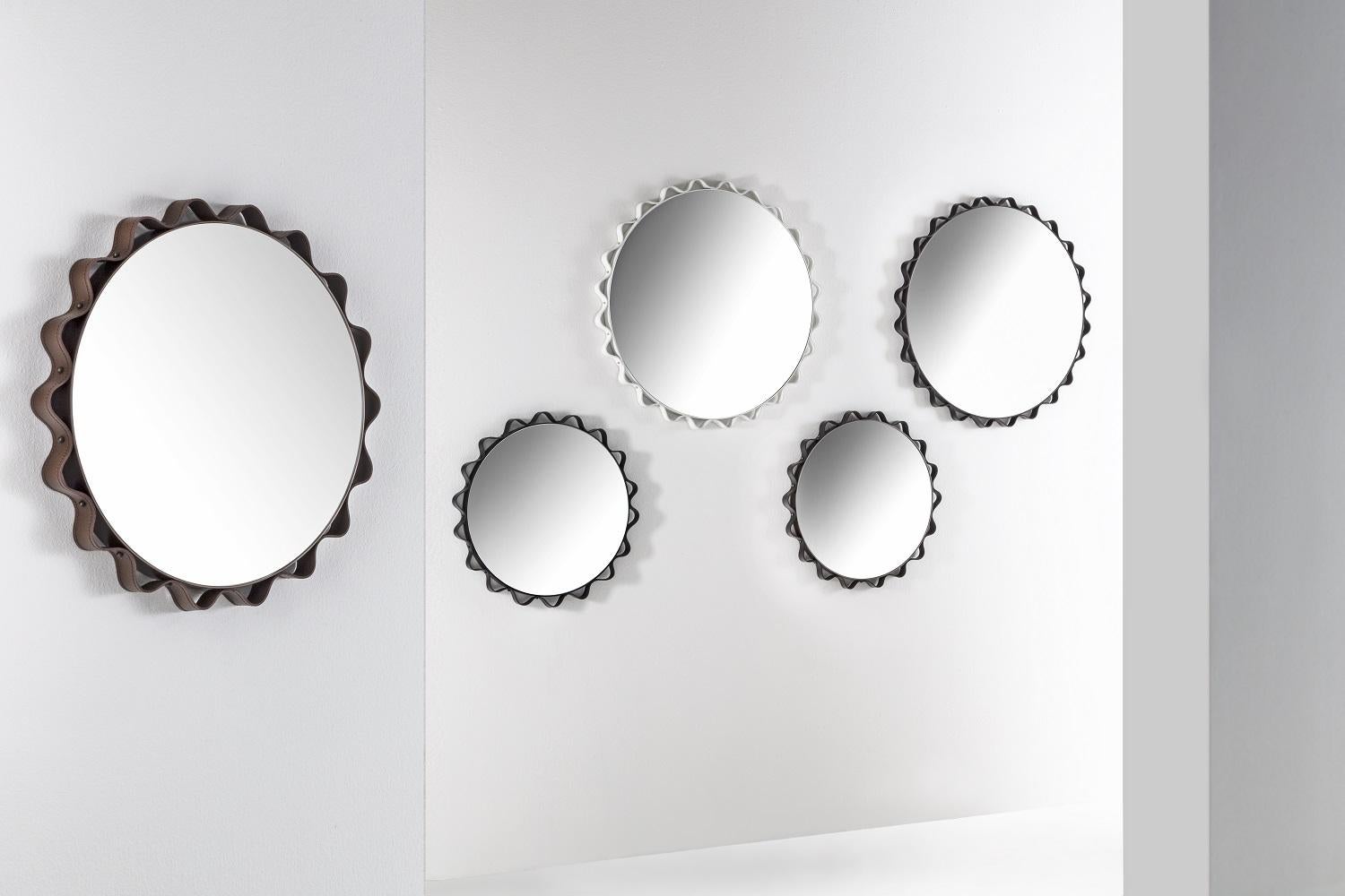 Modern Italian made leather mirror with a round shape available in two different sizes and a leather frame available in four colors. The diameter can be 53 cm or 73 cm and the leather frame can be white, black, moka or anthracite colors. Gold studs