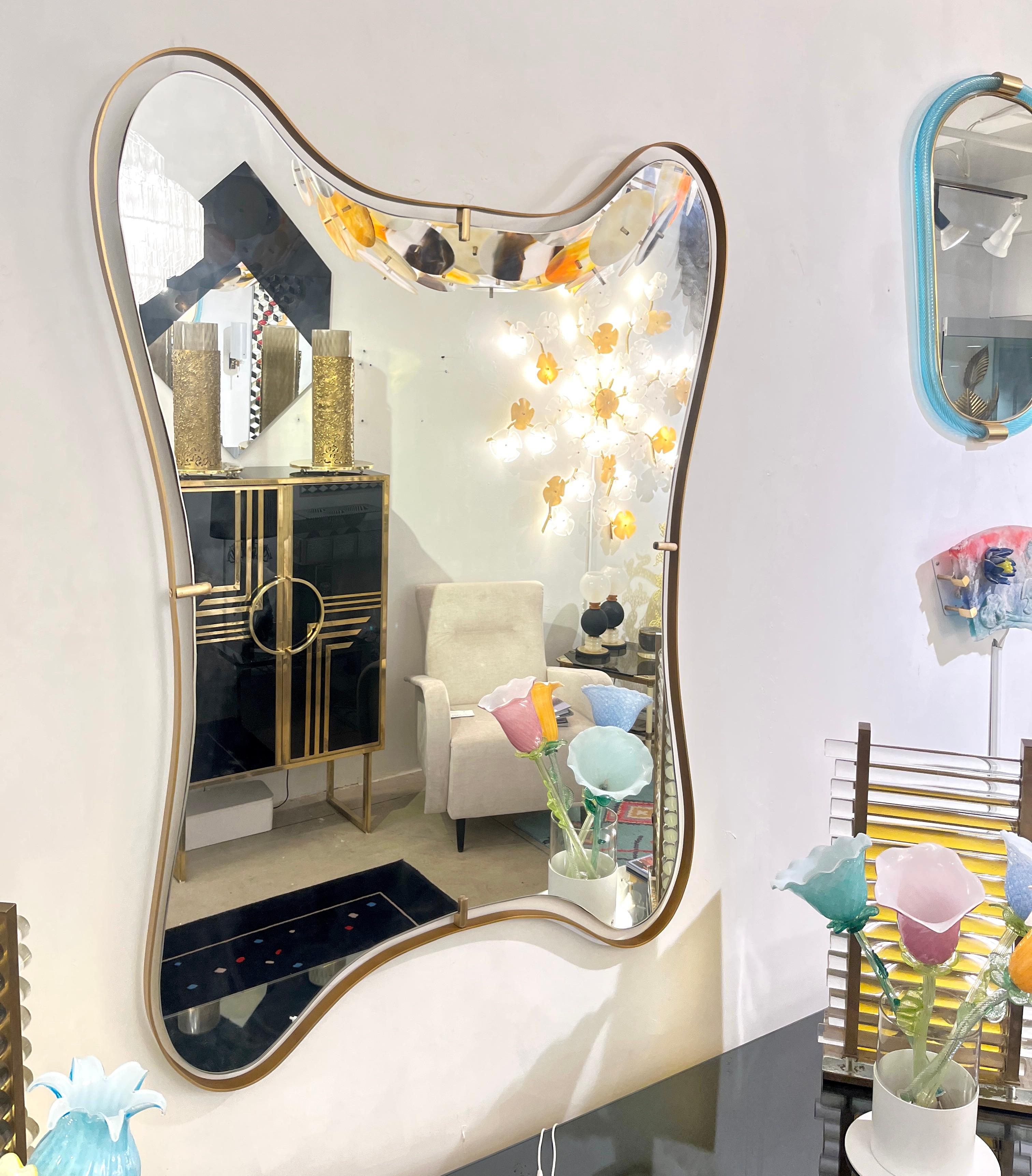 Contemporary Italian modern design mirror with elegant curved brass frame detached from the mirror in a floating design, entirely handcrafted, showing a sensual, smooth wavelike motion pattern.
The mirror ends in a slightly rounded edge and shows a