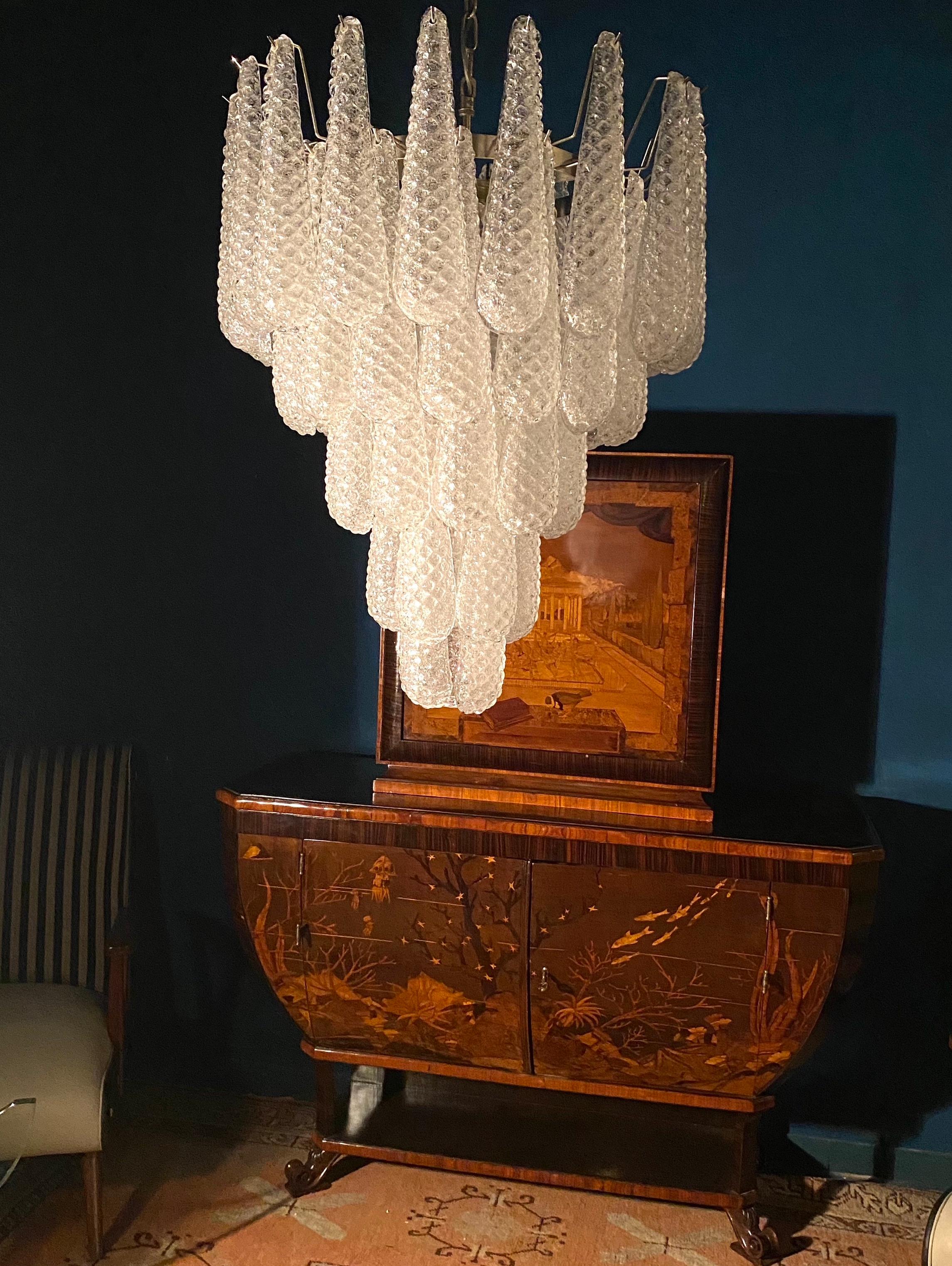 Feiner italienischer Murano-Kronleuchter aus 52 Glasblättern (transparentes Kristall, außen glatt, mit
Kristallpulver und dann rau innen.) mit einem Chromrahmen.
Zeitraum: 1970er-1980er Jahre.
Abmessungen: 75 cm (Zoll) Höhe ohne Kette; 26 Zoll (66