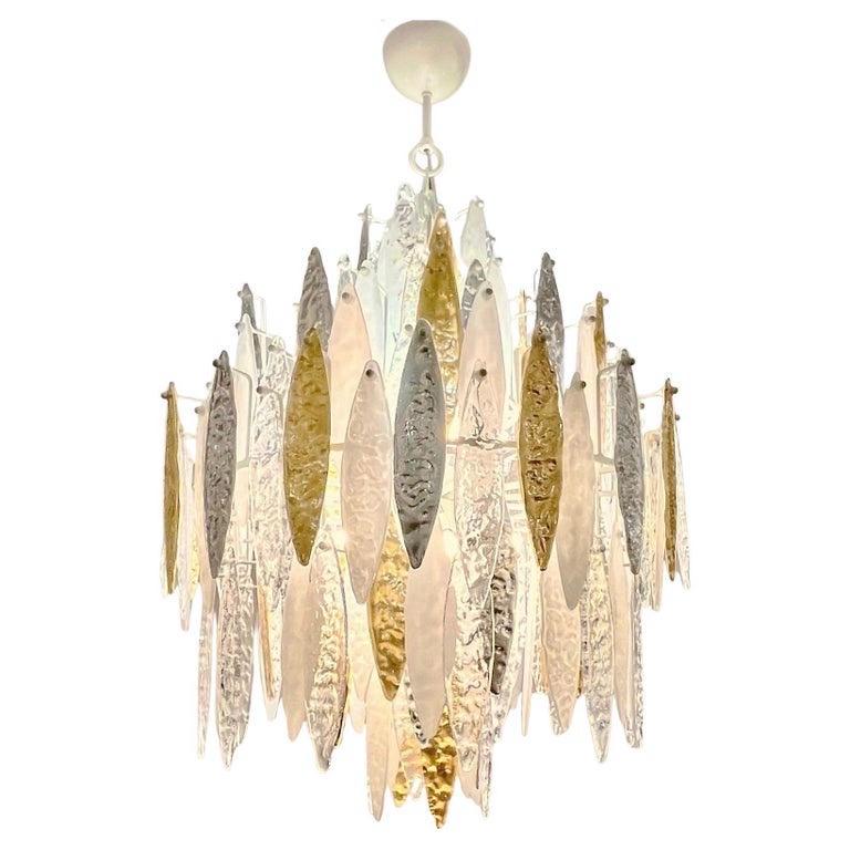 Le diverse gocce intercambiabili in vetro di Murano sono lavorate con una texture martellata, concava da un lato e in rilievo dall'altro, che crea movimento e riflette la luce in molti modi. Alcuni sono in vetro cristallino, altri sono lavorati su