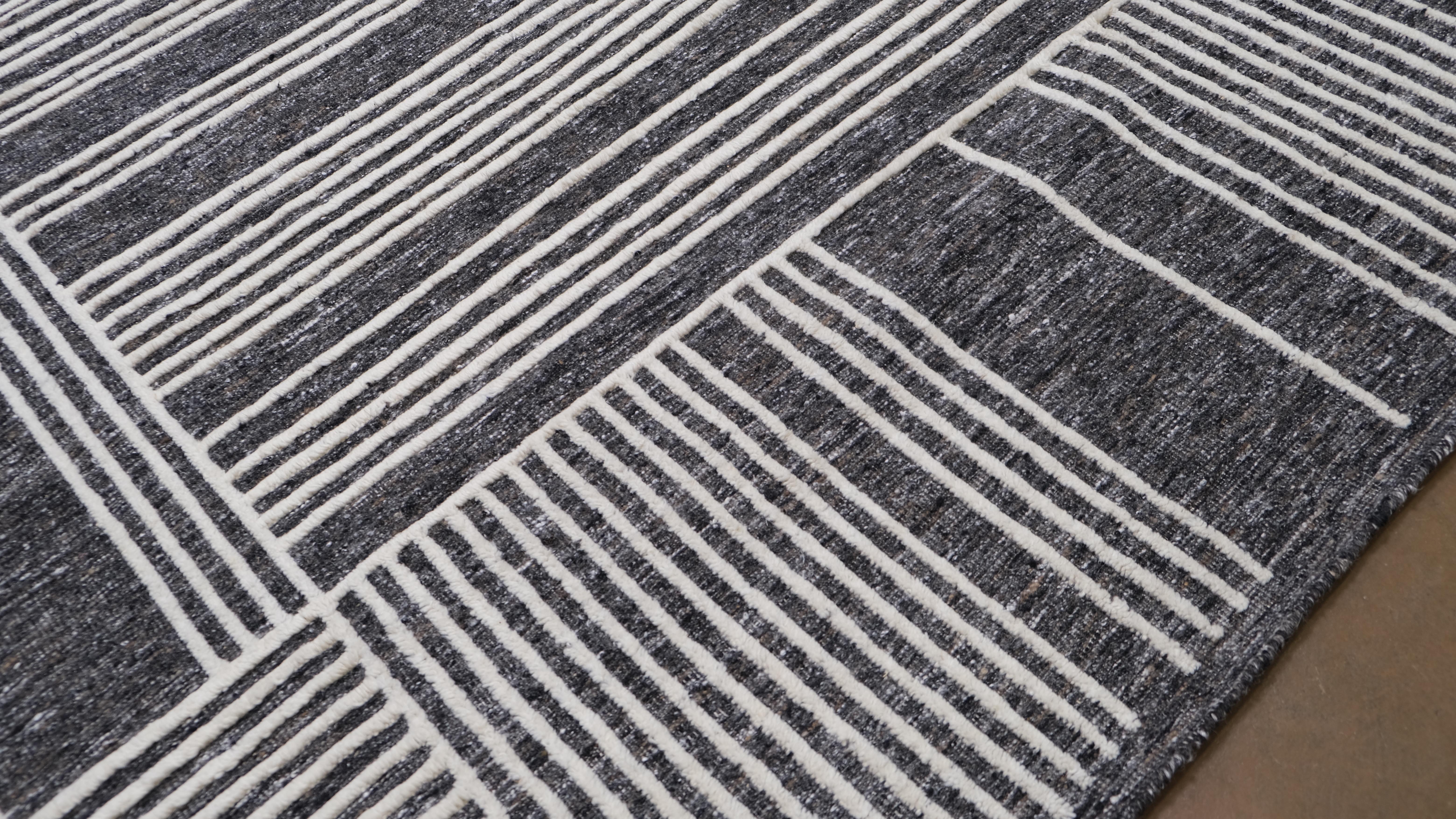 Verwandeln Sie Ihren Raum mit der kühnen Raffinesse dieses handgeknüpften Wollteppichs, der ein auffälliges geometrisches Muster in Grau und Elfenbein aufweist. Das komplizierte lineare Muster besteht aus abwechselnd vertikal und horizontal