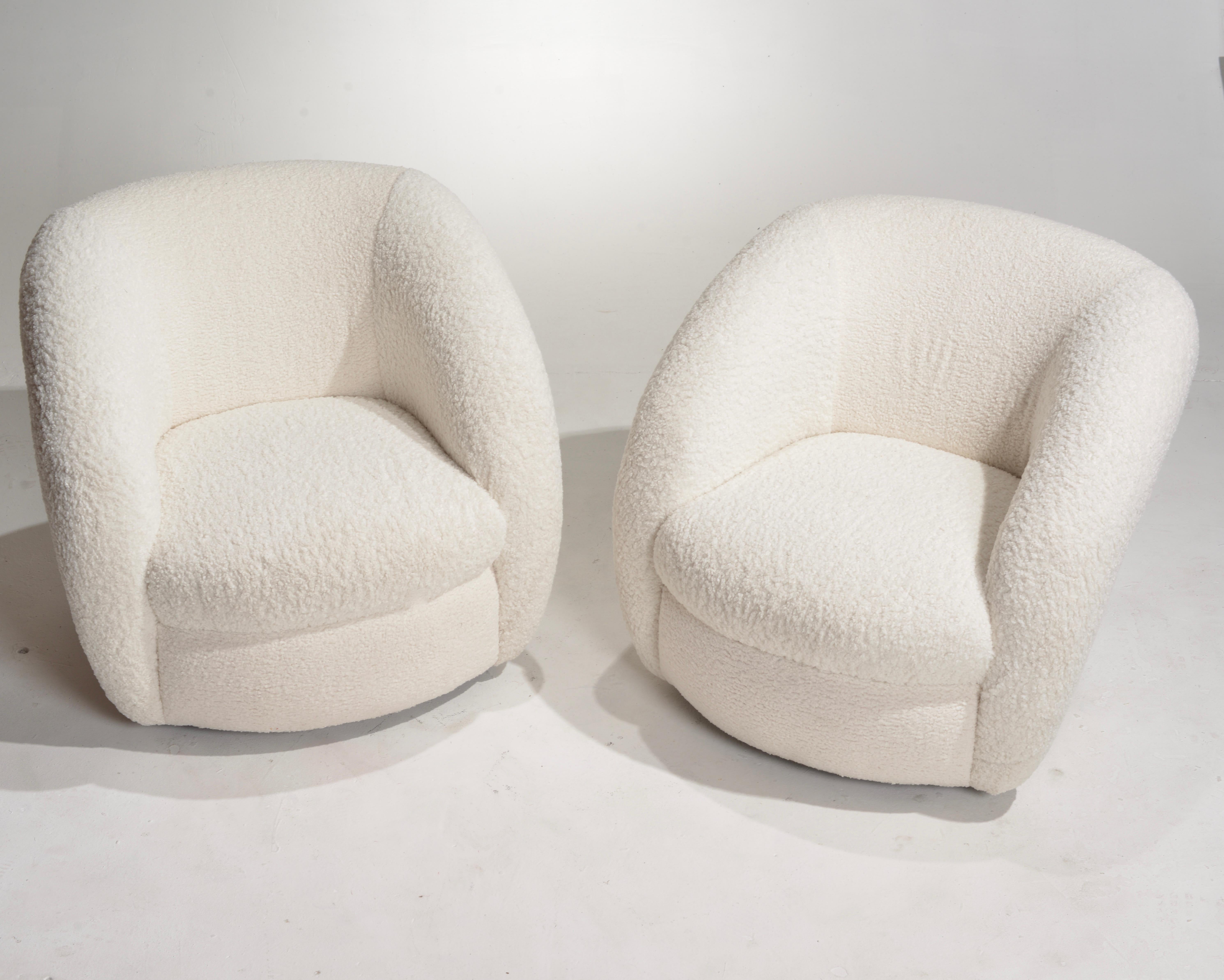 A duo of plush boucle vintage swivel lounge chairs featuring fresh upholstery in a textured bone white fabric. Large legless swivel base creates a minimal curved silhouette while raised arms connect to create the seat back.