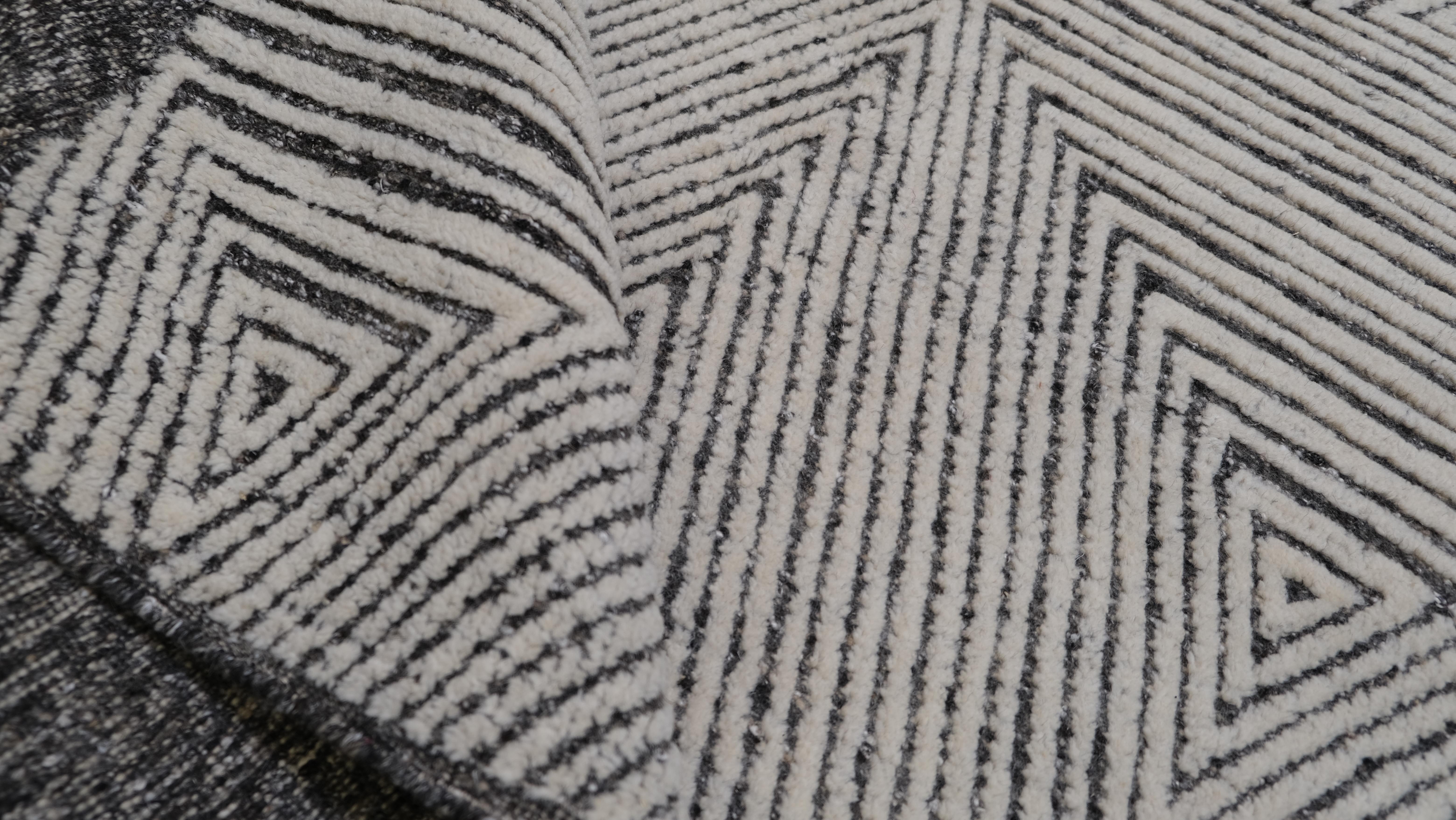 Ce tapis en laine nouée à la main, au motif géométrique triangulaire, rehausse votre espace d'un éclat artistique envoûtant. Le motif complexe de triangles concentriques crée un effet visuel dynamique, ajoutant du mouvement et de la profondeur à