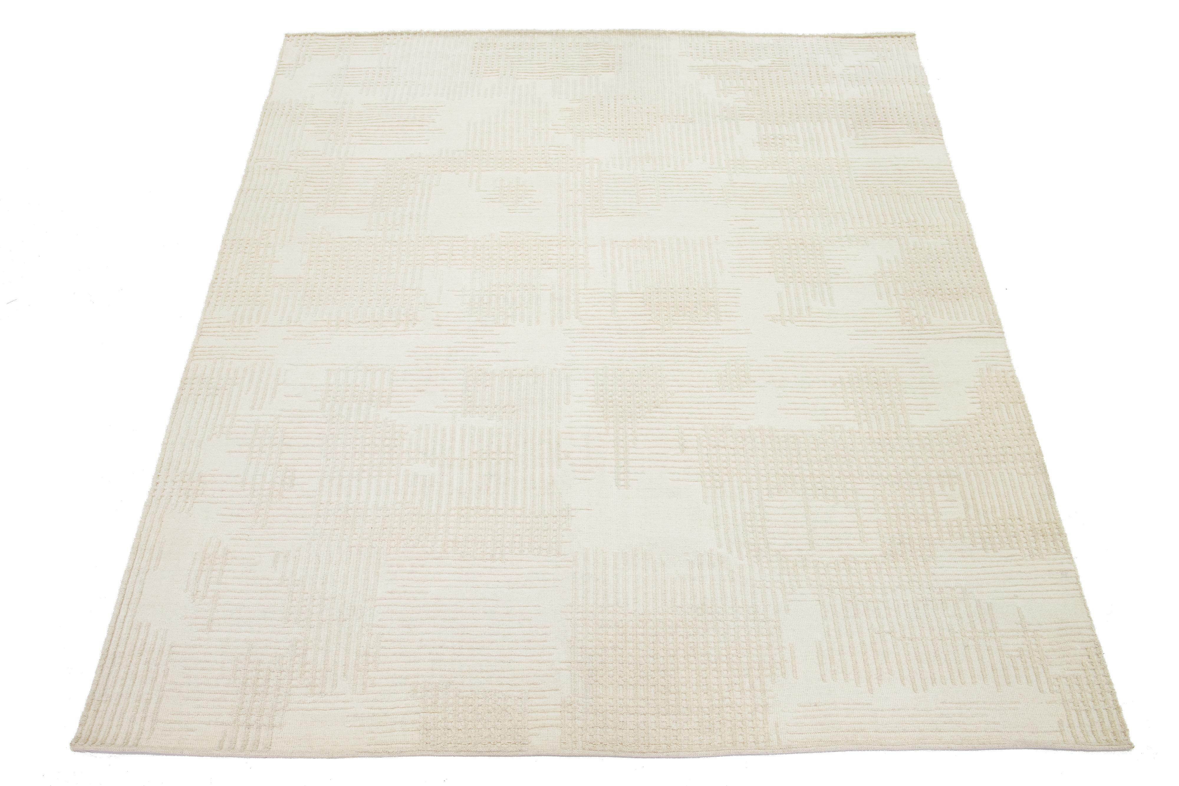 Questo tappeto contemporaneo in lana annodato a mano in stile marocchino presenta un lussuoso campo avorio e un audace disegno astratto e neutro.

Questo tappeto misura 9'1'' x 12'3''.

 