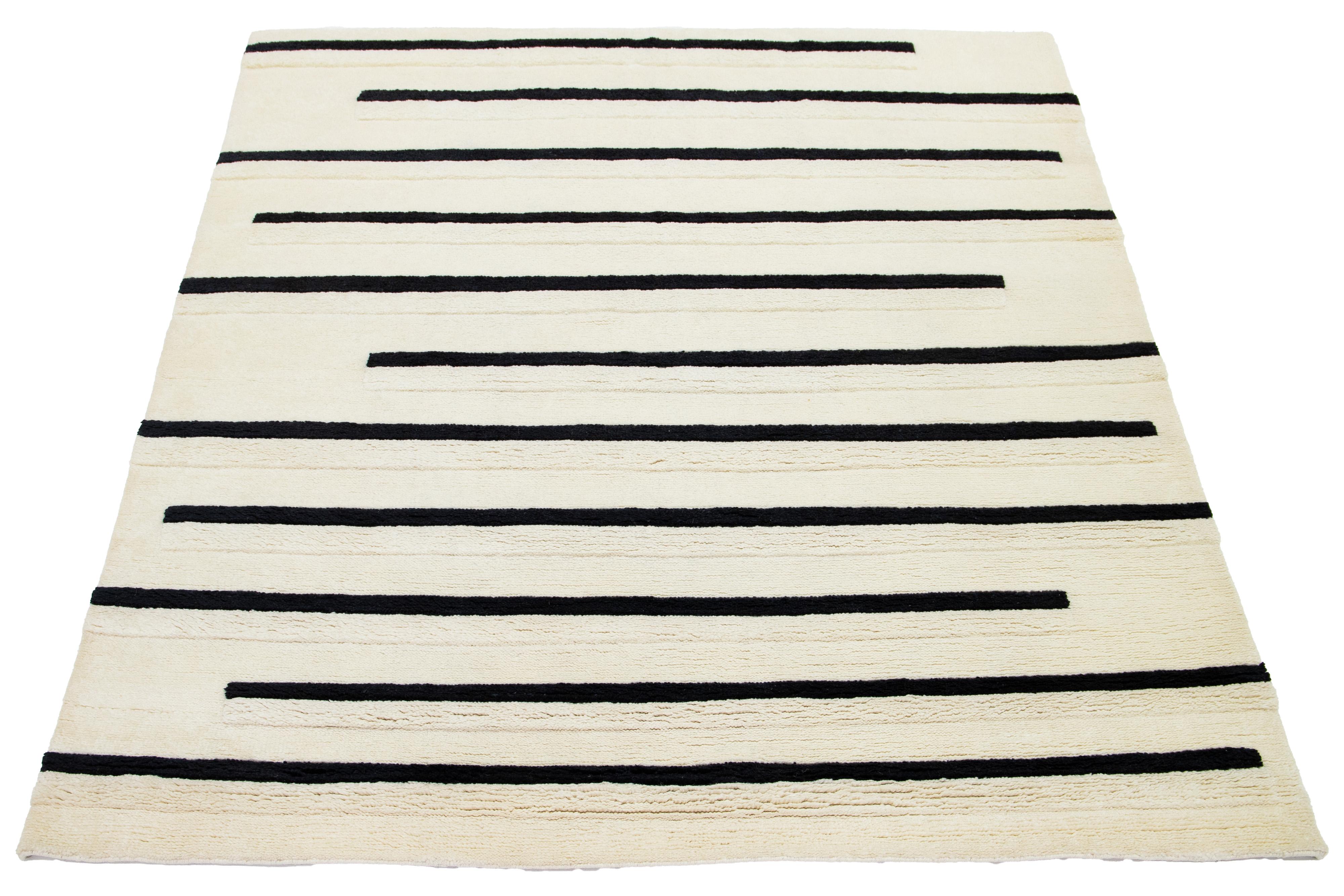 Beautiful contemporary Moroccan-style hand-knotted wool rug with an ivory field and a stunning black striped design.

This rug measures 8'3