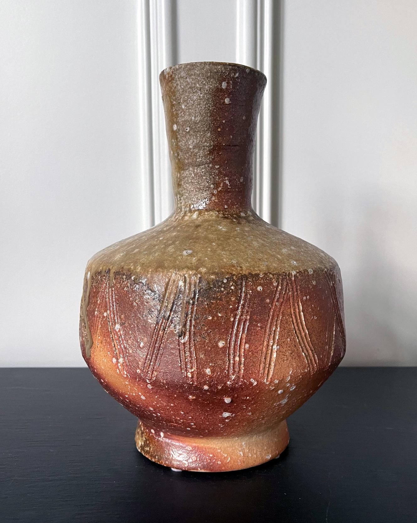 A tall ceramic vase made in the tradition of Shigaraki ware by Japanese potter Takahashi Shunsai (1927-2011), the fourth heir of the famed Rakusai lineage of potters. The vase is heavily potted in the reddish sandy Shigaraki clay. It has a Classic