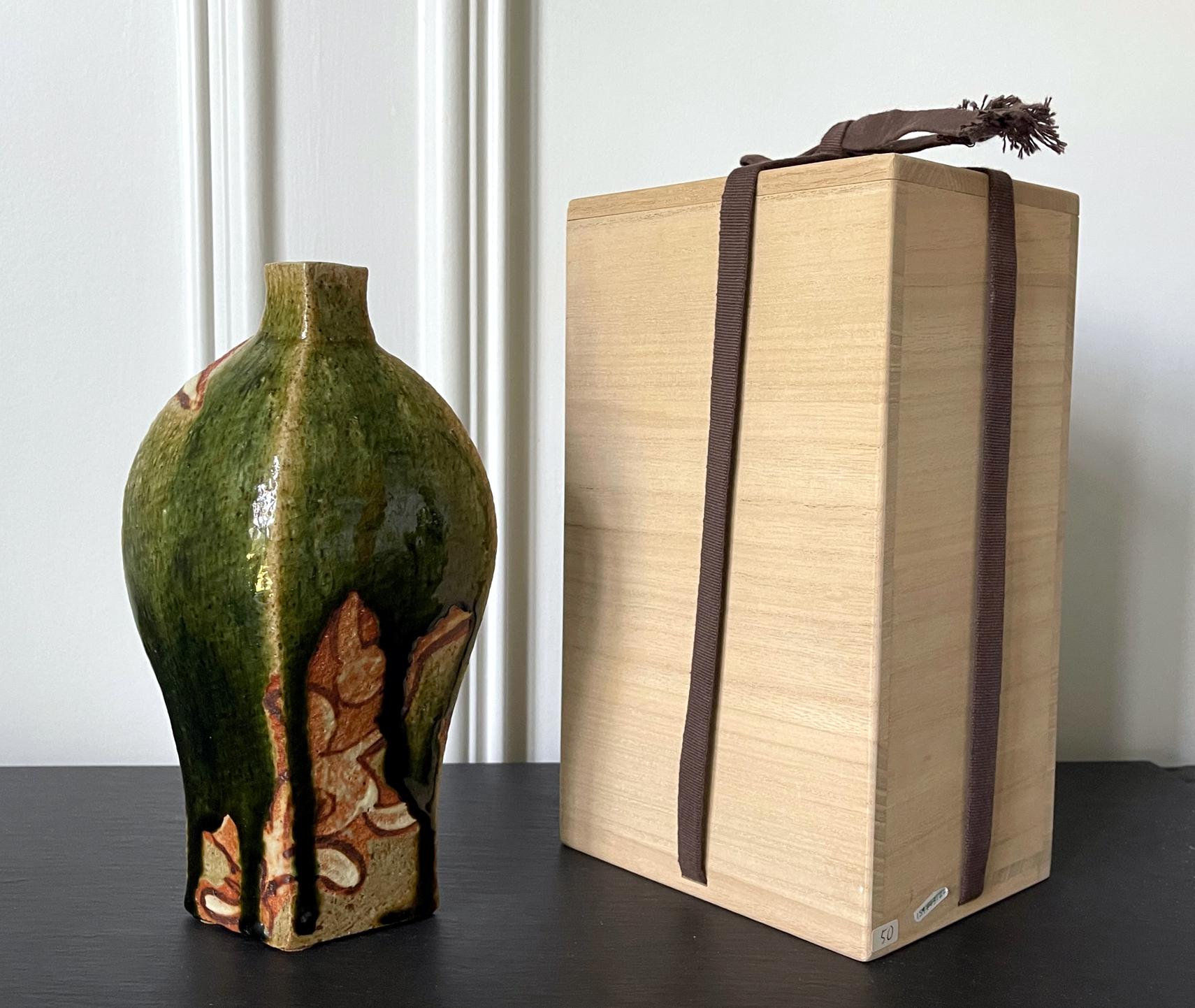 A contemporary studio ceramic vase made by Japanese potter Ken Matsuzaki (1950-). The vase showcases a geometrical spindle form, rather distinguishingly modern. It is covered with a thick dripping Oribe green glaze partially revealing the unglazed