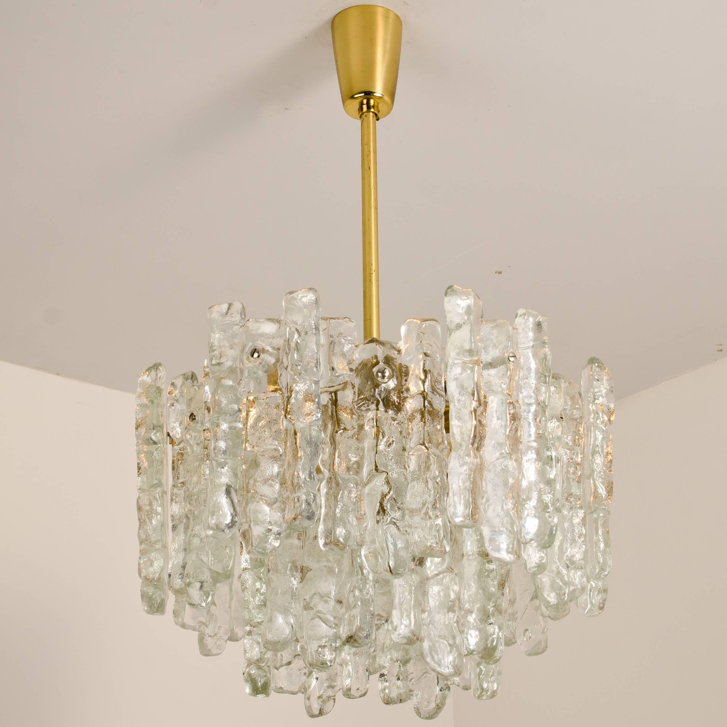 A very beautiful and elegant modern brass chandelier, manufactured by Kalmar Austria in the 1970s. Lovely design, each chandelier has eight sockets (E27) and two layers of extremely stylish textured solid ice glass sheets (18 pieces) dangling on it.