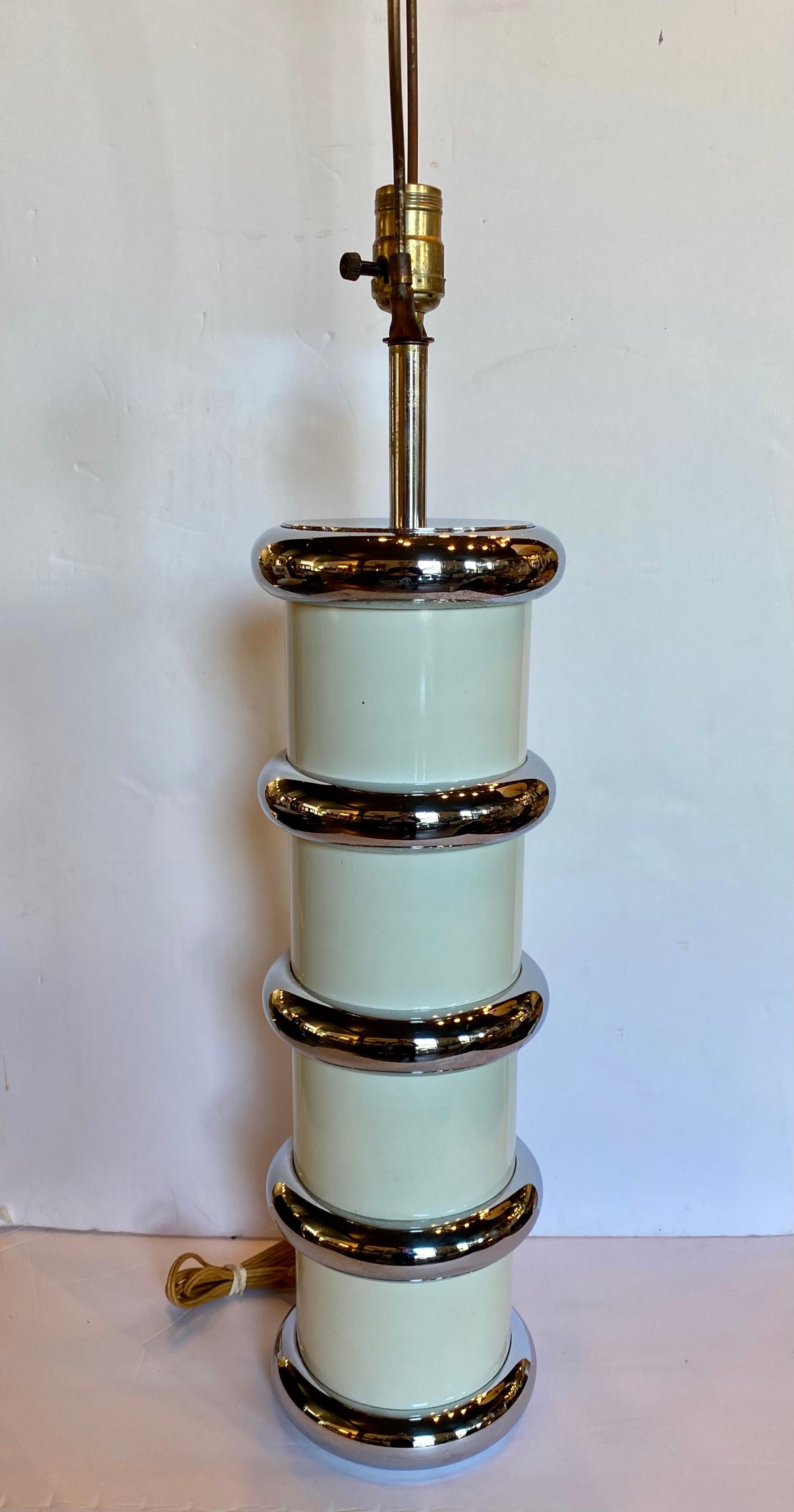 Mid-Century Modern chromed metal and enamel table lamp by Mutual Sunset Lamp Company. This tall round cylinder shaped lamp features an ivory/cream enamel column wrapped with stacked chromed metal bullnose rings. In the style of Karl Springer. Lamp
