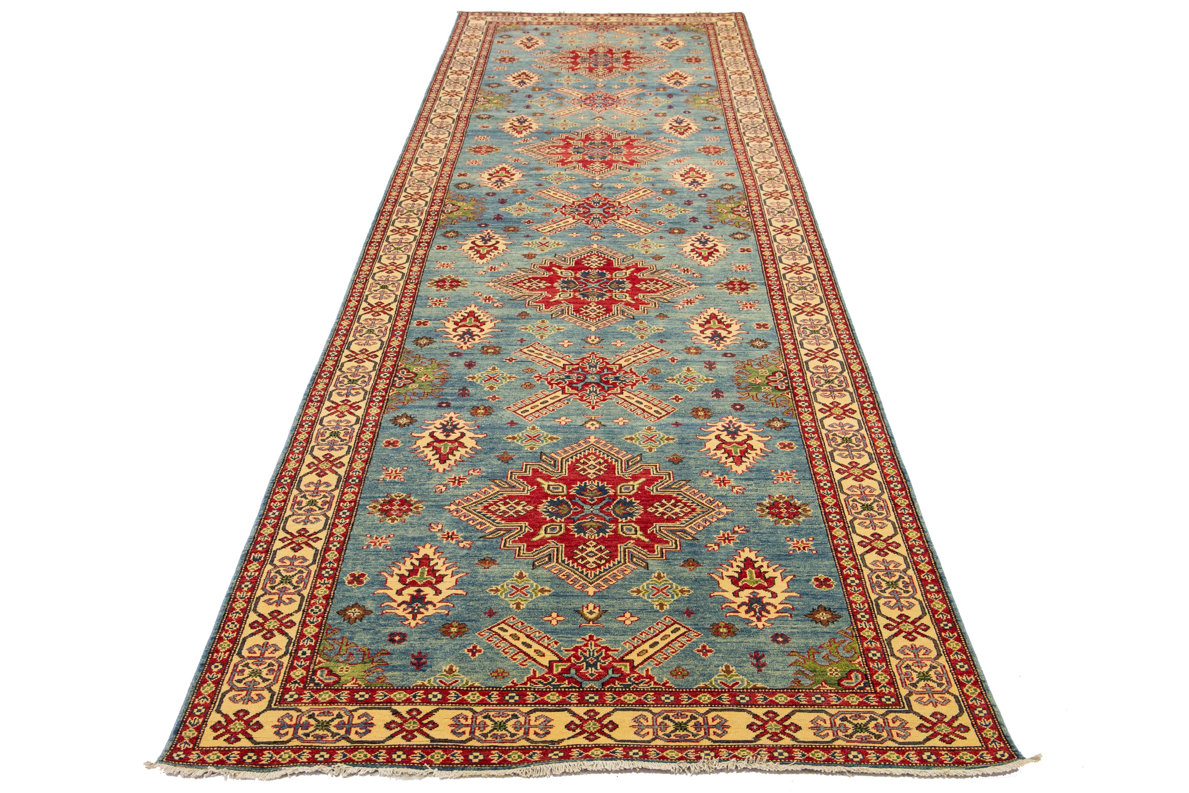 This Kazak wool rug is crafted with meticulous attention to detail through traditional hand-weaving techniques. It features a sophisticated blue color palette, enhanced by elegant embellishments in shades of red, green, and beige. The rug is