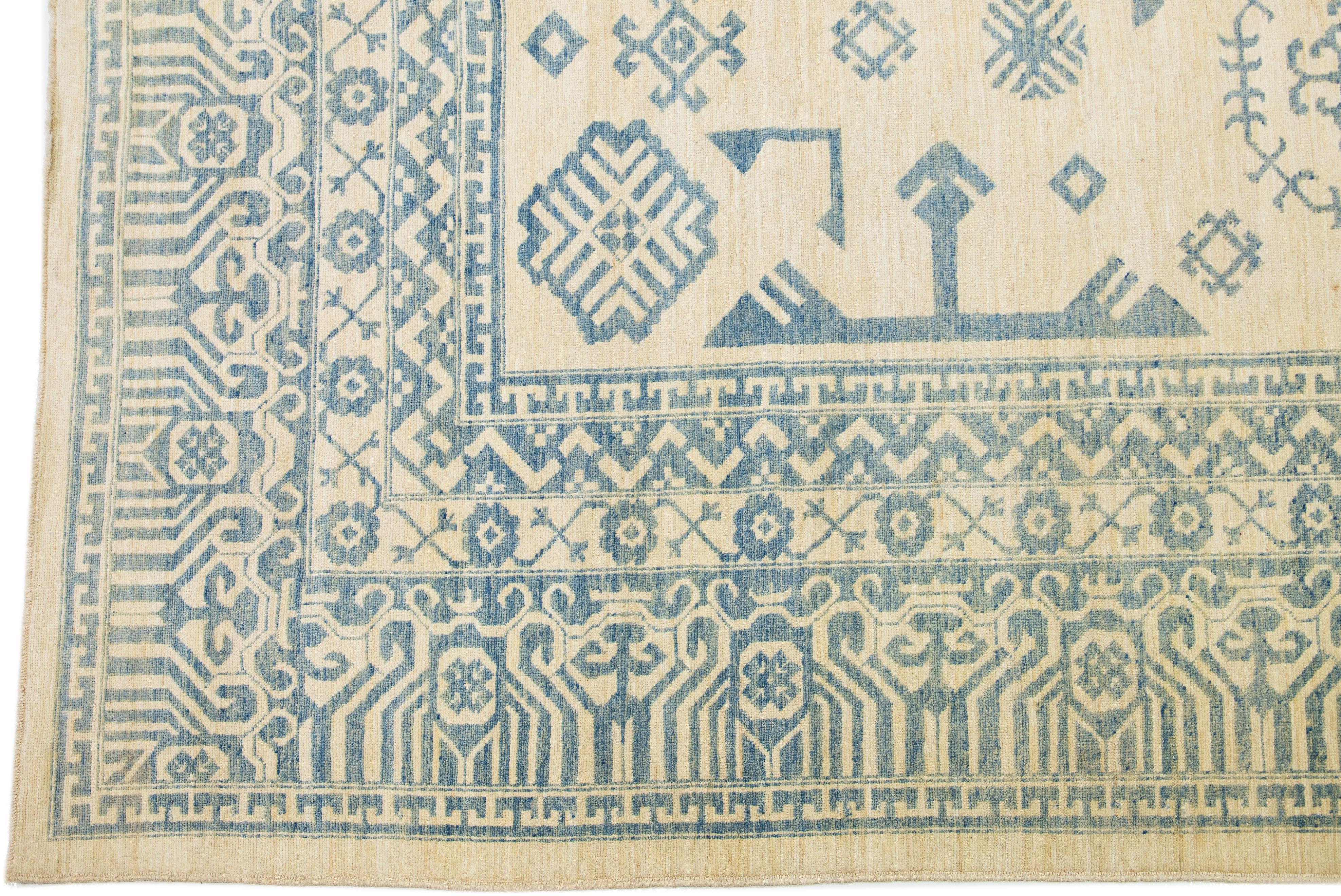 Beautiful Modern Khotan hand-knotted wool beige field. This Khotan rug has a beautifully designed frame and accent of blue in a gorgeous all-over geometric pattern design.

This rug measures 13'1 