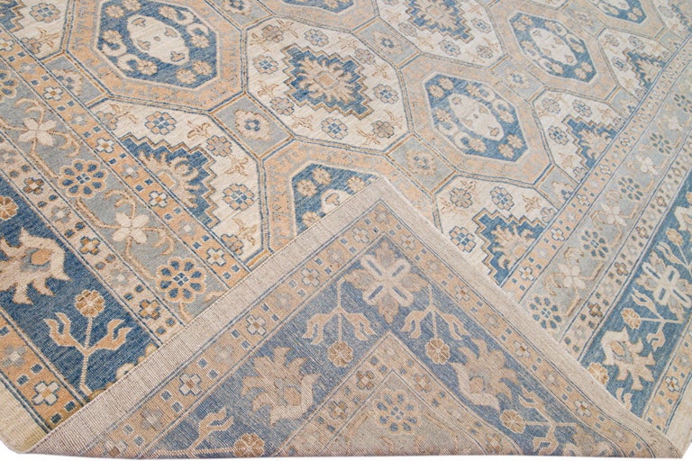 Beautiful Modern Khotan hand-knotted wool beige field. This Khotan rug has a beautifully designed frame and accent of orange, peach, and blue in a gorgeous all-over geometric floral pattern design.

This rug measures 13' 2